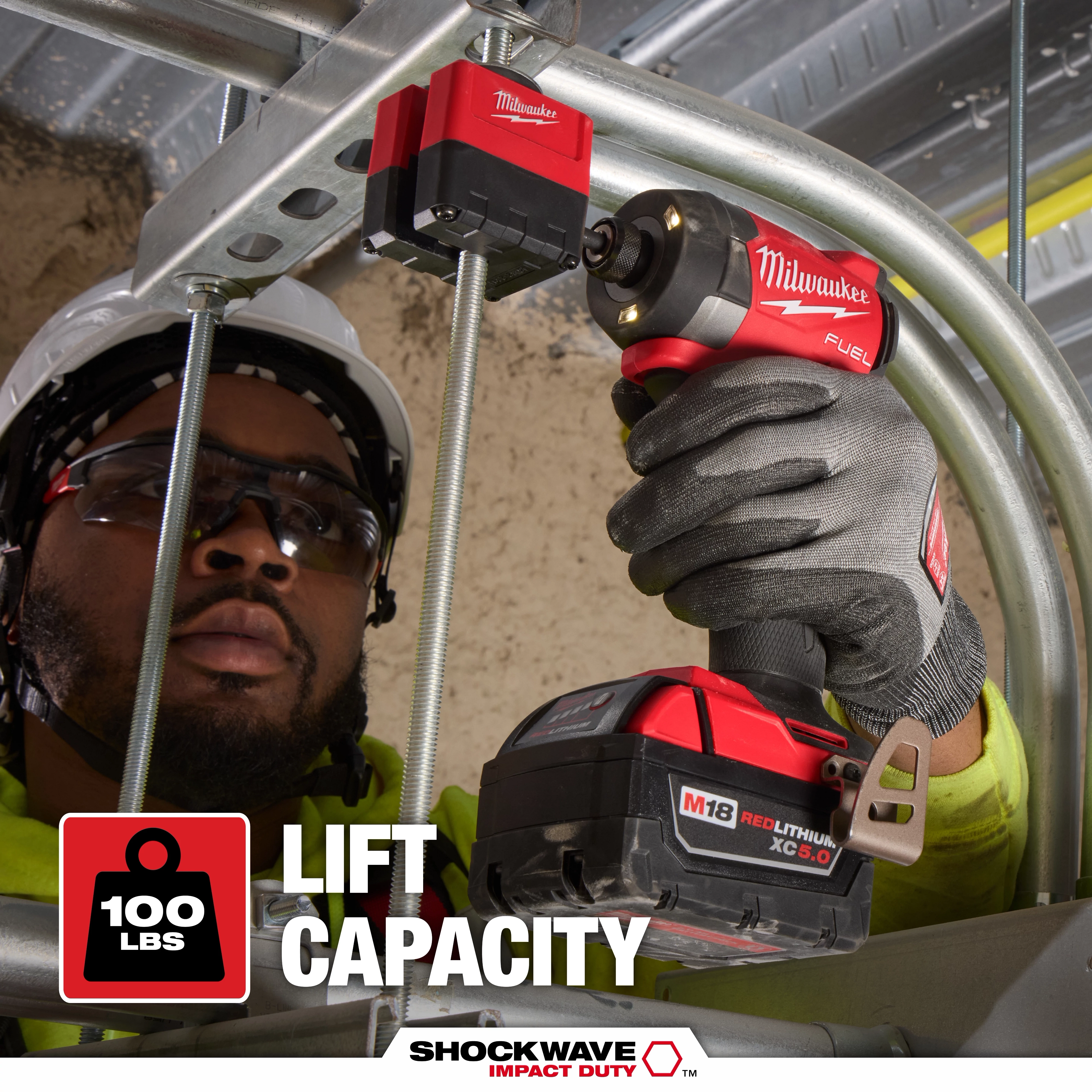 A person uses the SHOCKWAVE™ Impact Duty 3/8" Threaded Rod Nut Runner by Milwaukee, showing its capacity to lift 100 lbs. The tool is held in a gloved hand.