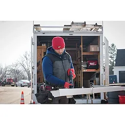 Image of a man on a jobsite wearing the Milwaukee Rib-Knit Cuffed Beanie in red