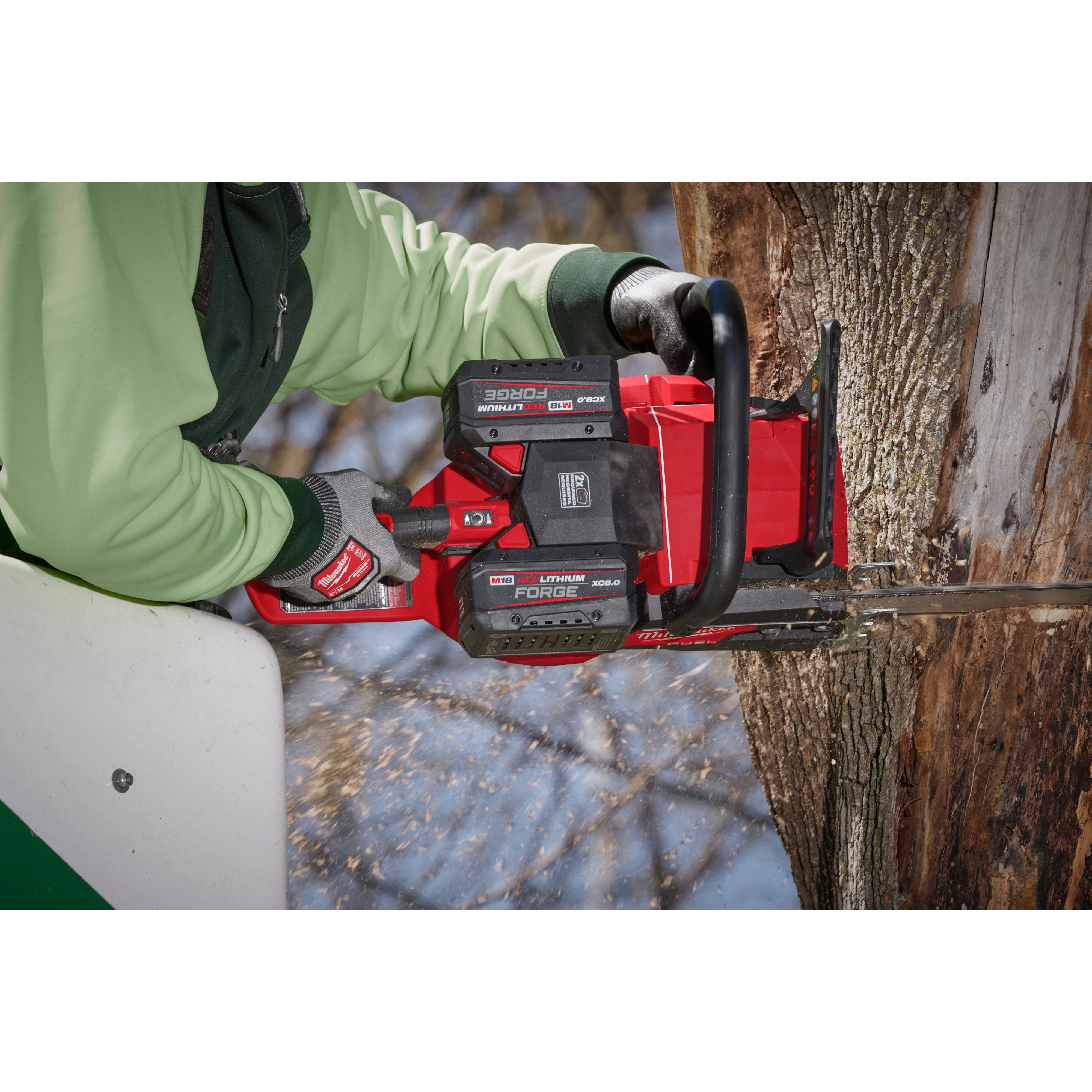 A person uses a red chainsaw equipped with the M18 REDLITHIUM FORGE XC8.0 Battery Pack to cut into a tree trunk.