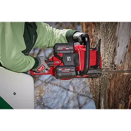 A person uses a red chainsaw equipped with the M18 REDLITHIUM FORGE XC8.0 Battery Pack to cut into a tree trunk.