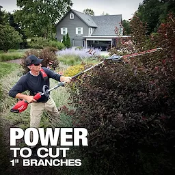 Person trimming tall bushes with an M18 FUEL QUIK-LOK Articulating Hedge Trimmer Attachment in a yard near a house.