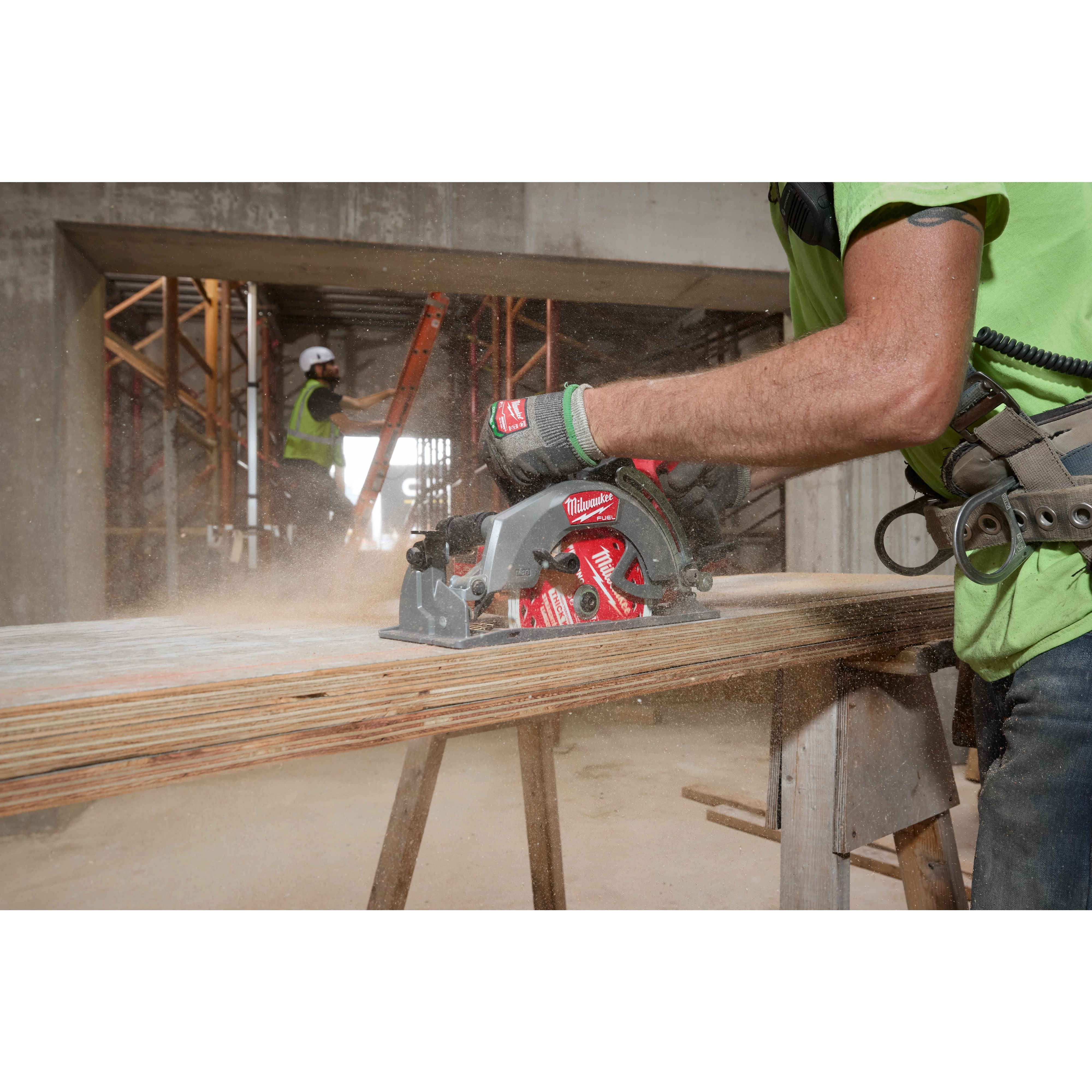Worker using M18 FUEL 7-1/4" Rear Handle Circular Saw with ONE-KEY to cut wood on a construction site, wearing safety gear.