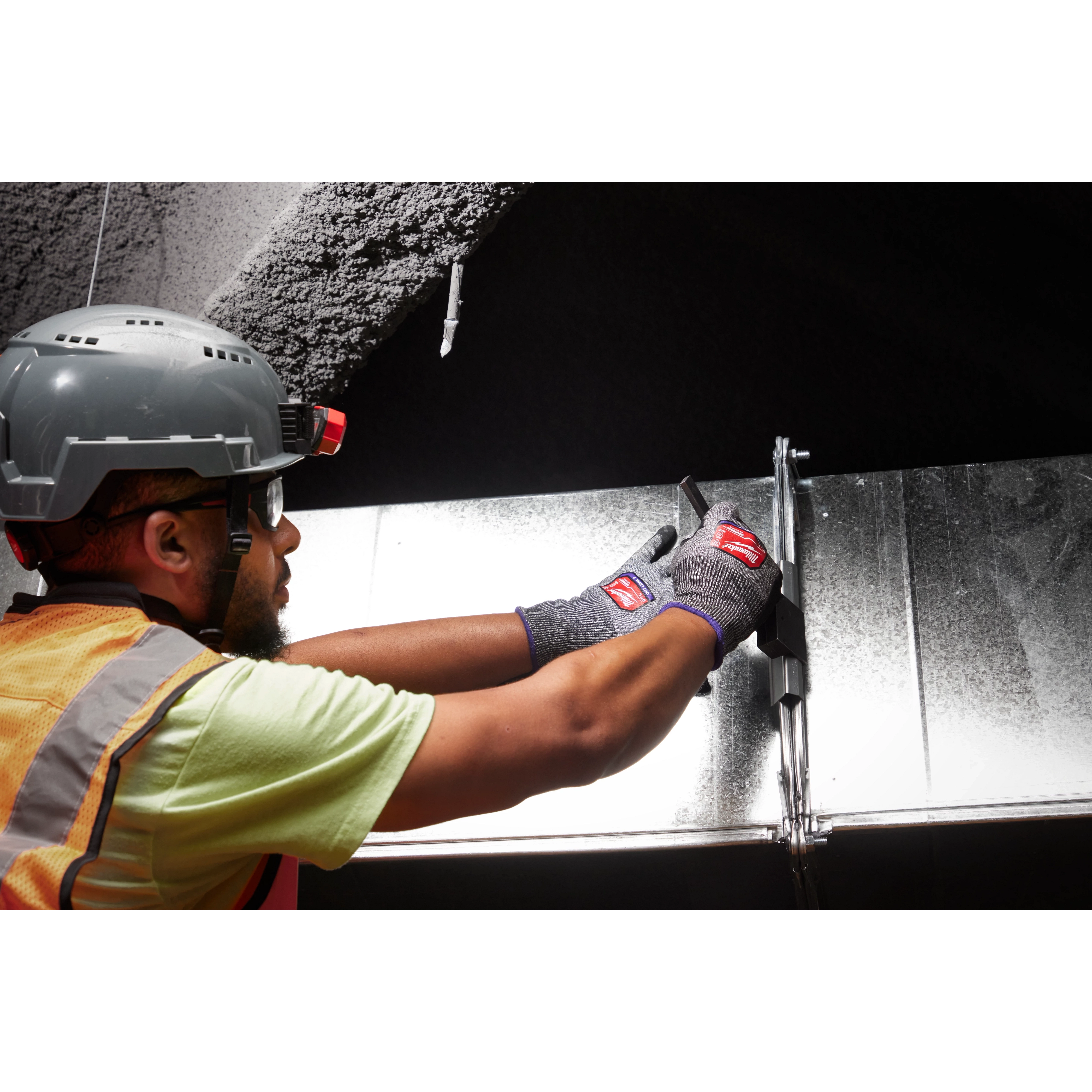 Person working with metal wearing Cut Level 7 High-Dexterity Nitrile Dipped Gloves - L, protective helmet, and safety vest.
