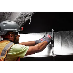 Person working with metal wearing Cut Level 7 High-Dexterity Nitrile Dipped Gloves - L, protective helmet, and safety vest.