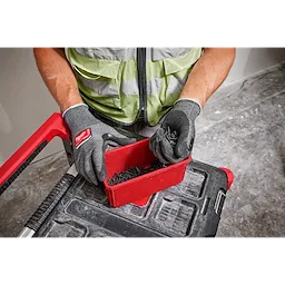Person wearing Cut Level 2 High-Dexterity Nitrile Dipped Gloves - L handling screws from a red container on a workbench.