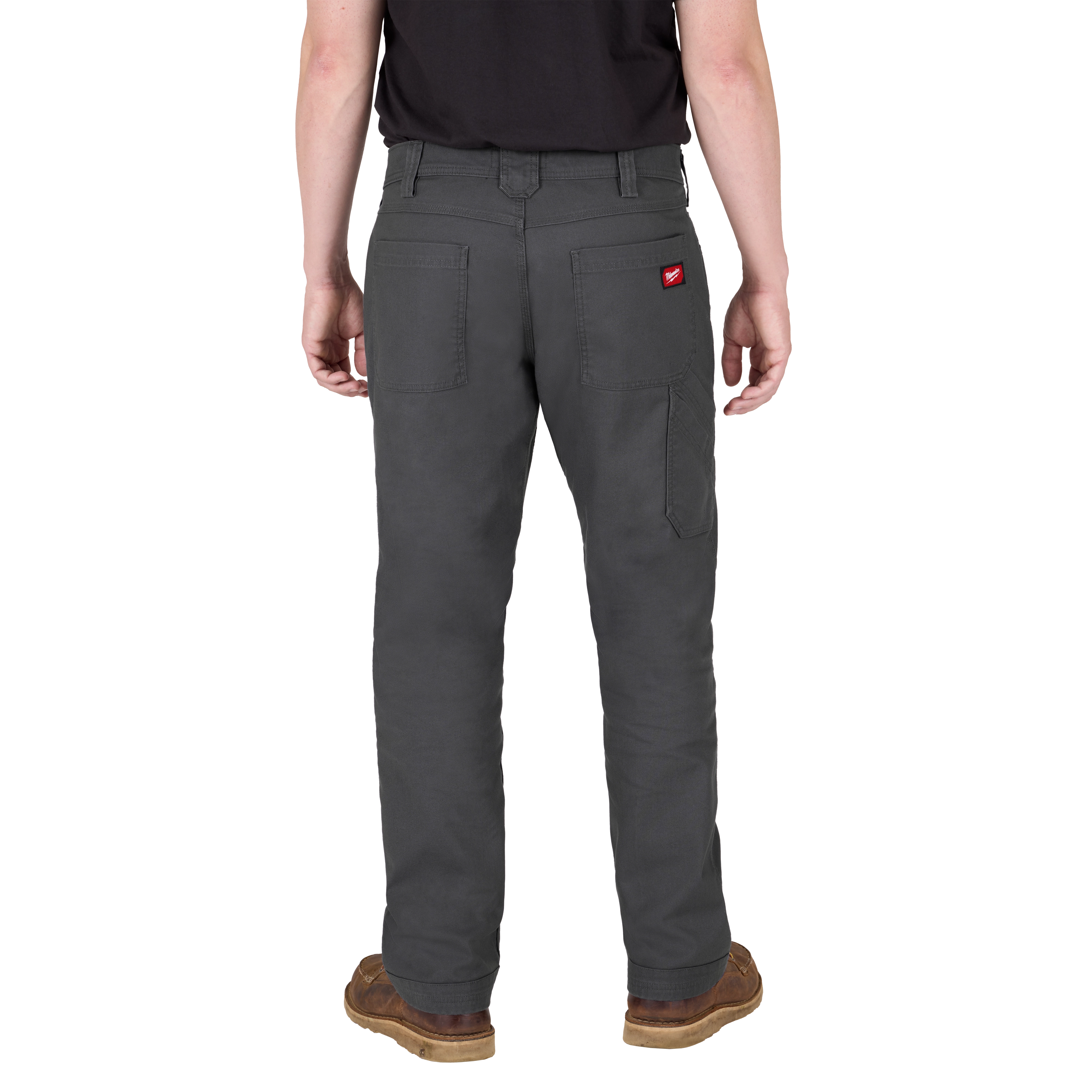 A person is seen from the back wearing dark gray utility pants with multiple pockets and a small red tag on the right pocket. The person is also wearing a black shirt and brown shoes.