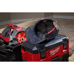 Flat Brim Snapback cap with construction pattern rests on a red and black toolbox, surrounded by power tools on a wooden surface.