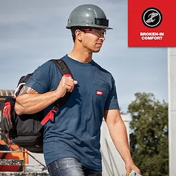 A man wearing a blue GRIDIRON Pocket T-Shirt - Short Sleeve with a helmet and carrying a backpack, labeled "Broken-in comfort".