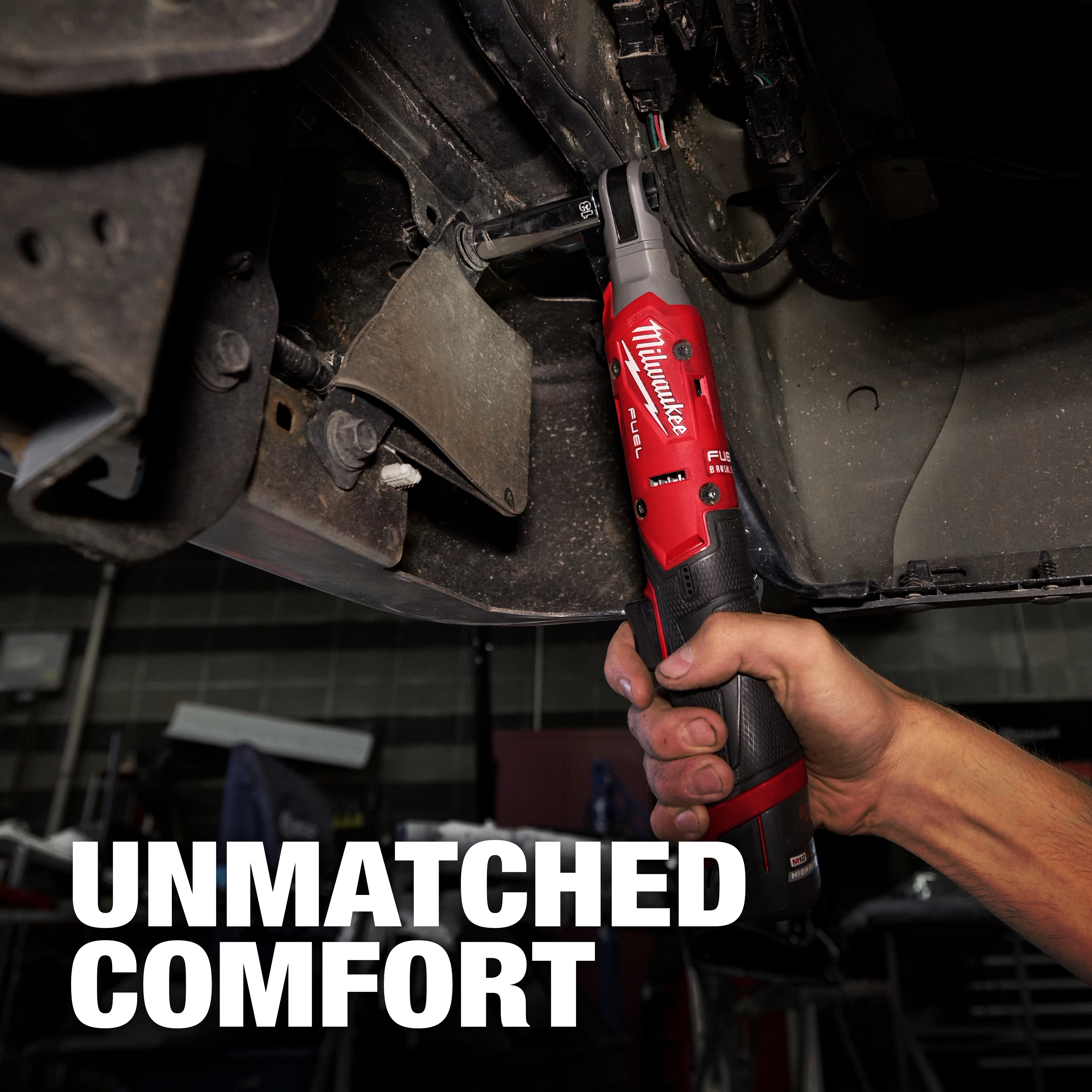 The M12 FUEL™ 3/8" Ratchet is held by a person working under a vehicle, showcasing its ergonomics and design. The background text reads "UNMATCHED COMFORT."