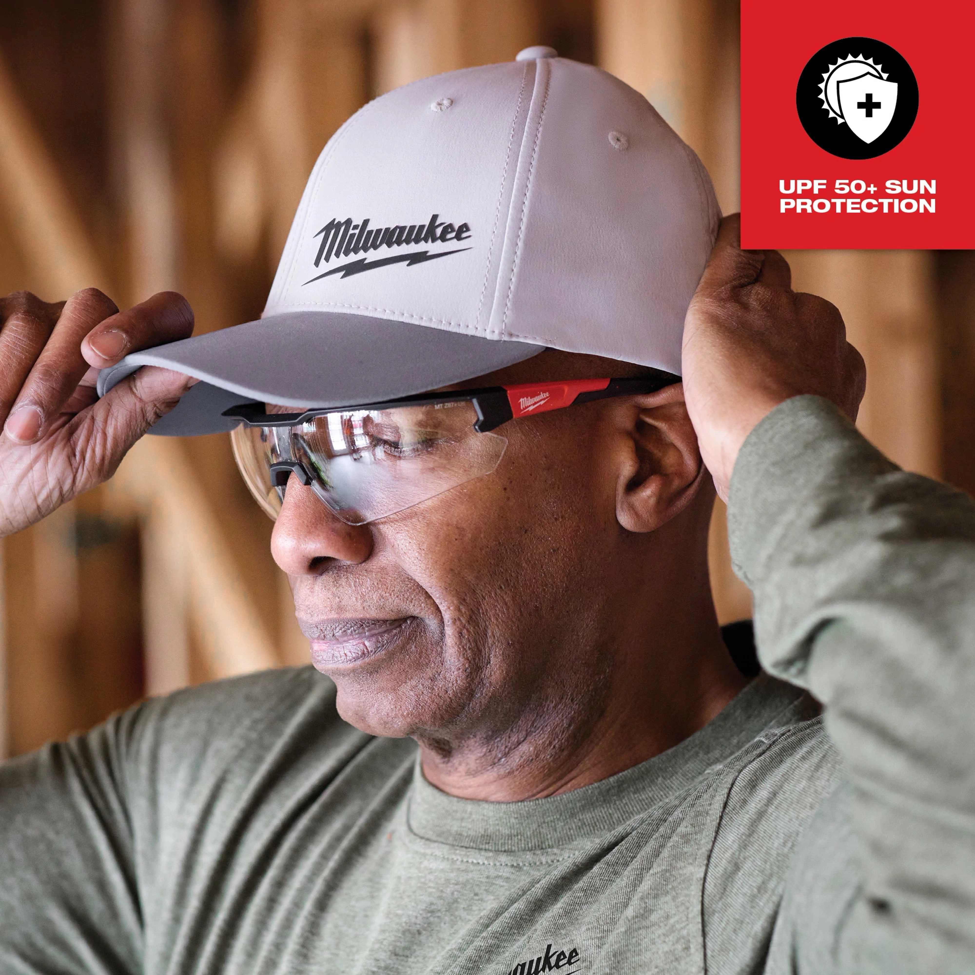 The WORKSKIN Performance Fitted Hat in gray has UPF 50+ sun protection. A person wearing it adjusts the brim.