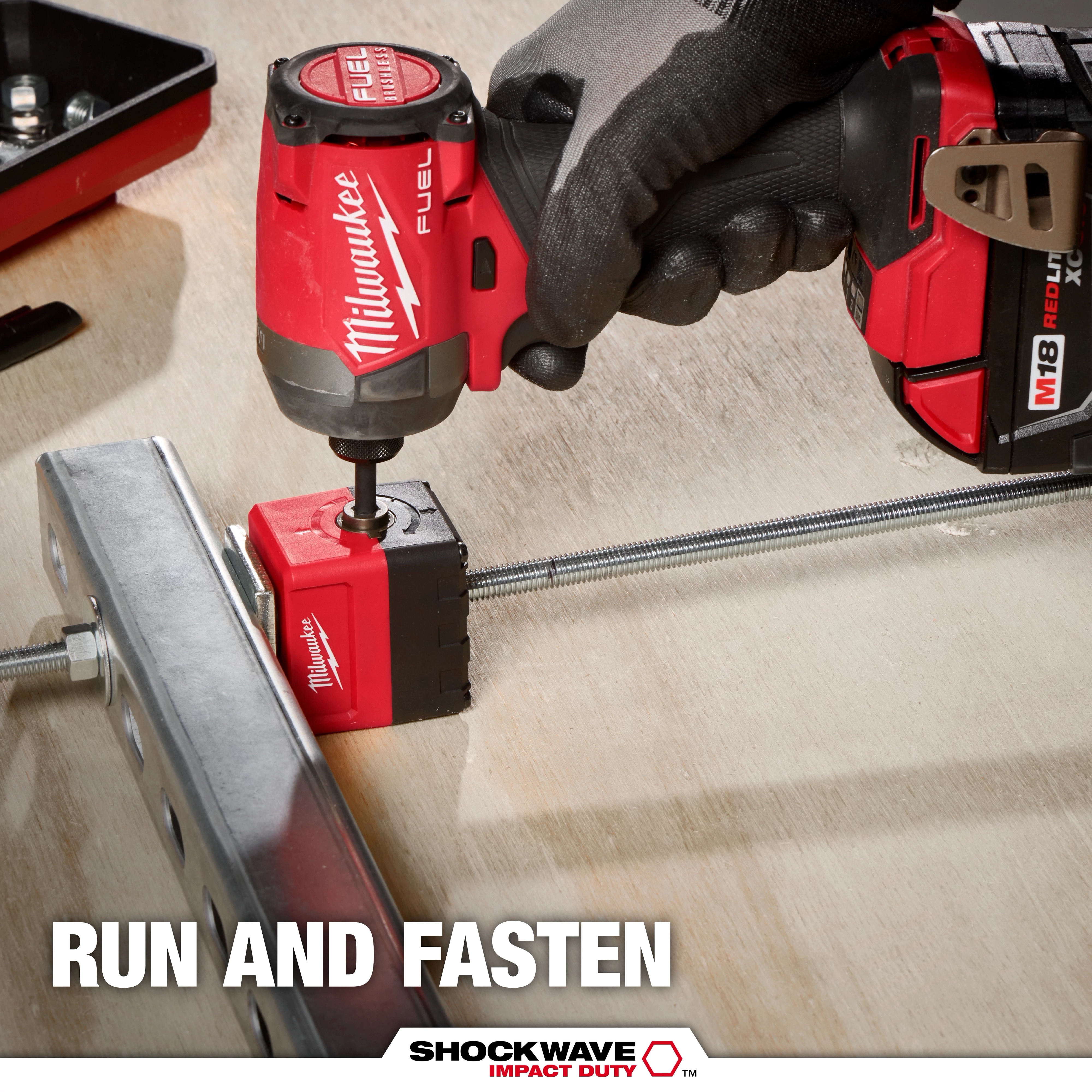 A Milwaukee power tool is used with the SHOCKWAVE™ Impact Duty 3/8" Threaded Rod Nut Runner to fasten a threaded rod to a metal bracket. The image includes branding and the slogan "Run and Fasten" at the bottom.