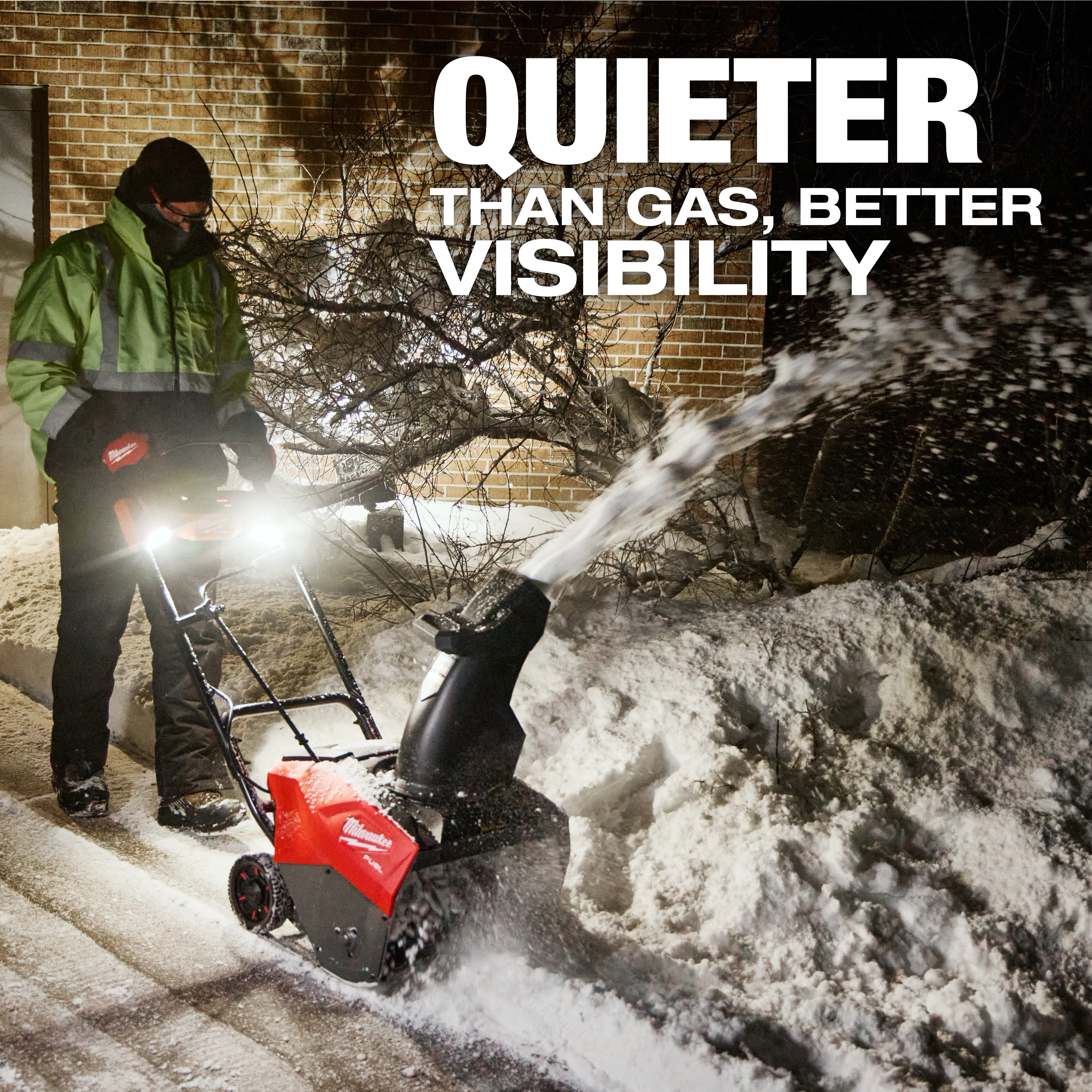 M18 FUEL™ 21" Auger Propelled Dual Battery Single Stage Snow Blower in use, clearing a path with light illumination. Snow is being actively expelled from the chute. Text on image reads "Quieter Than Gas, Better Visibility." A person operates the snow blower, dressed in winter attire.