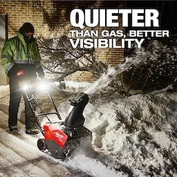 M18 FUEL™ 21" Auger Propelled Dual Battery Single Stage Snow Blower in use, clearing a path with light illumination. Snow is being actively expelled from the chute. Text on image reads "Quieter Than Gas, Better Visibility." A person operates the snow blower, dressed in winter attire.