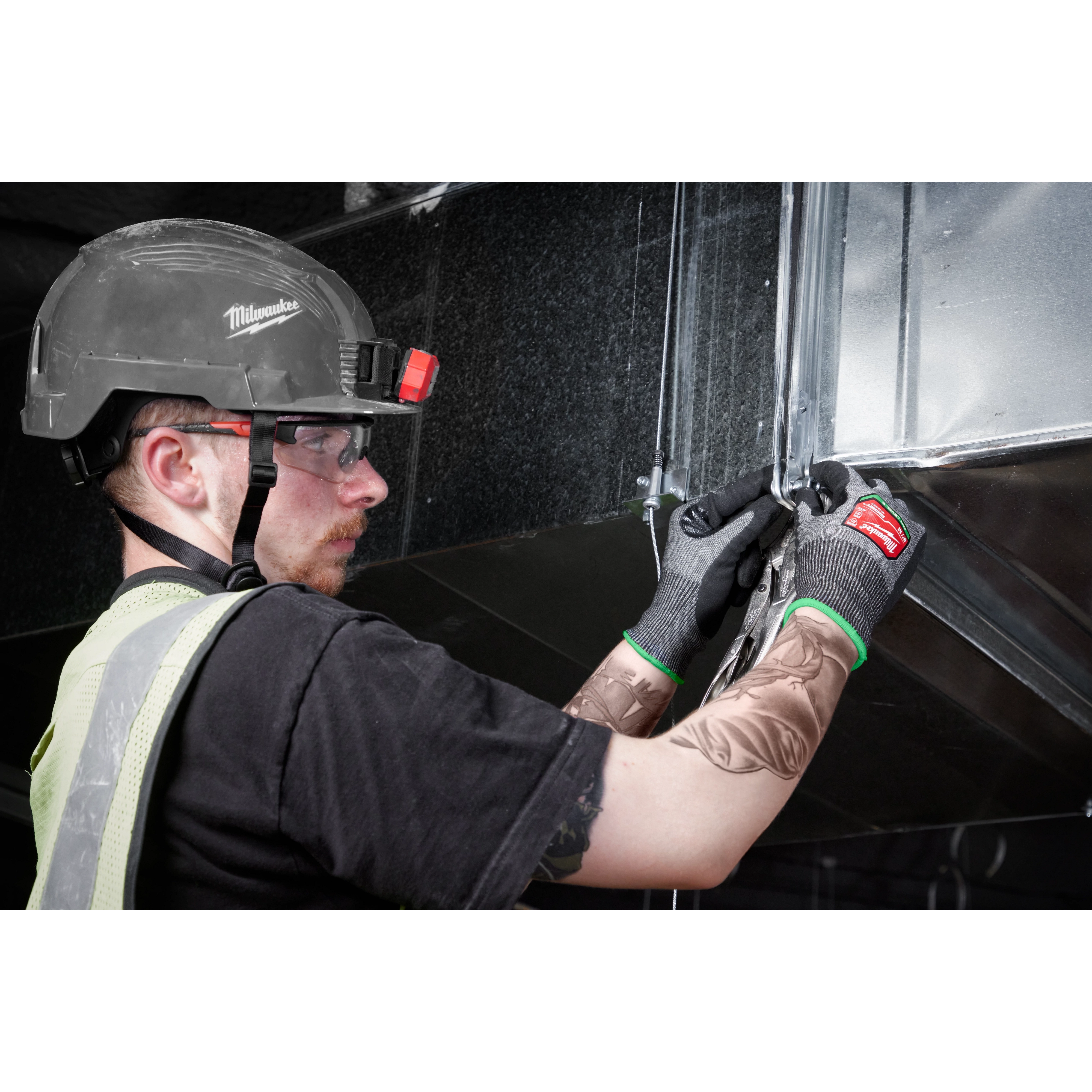 Worker wearing Cut Level 6 High-Dexterity Nitrile Dipped Gloves - L while using pliers on a metallic structure.