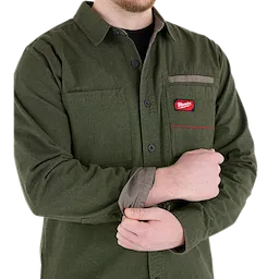 Man wearing a green GRIDIRON Flannel Shirt, adjusting the cuff. The shirt features a chest pocket with a red logo.