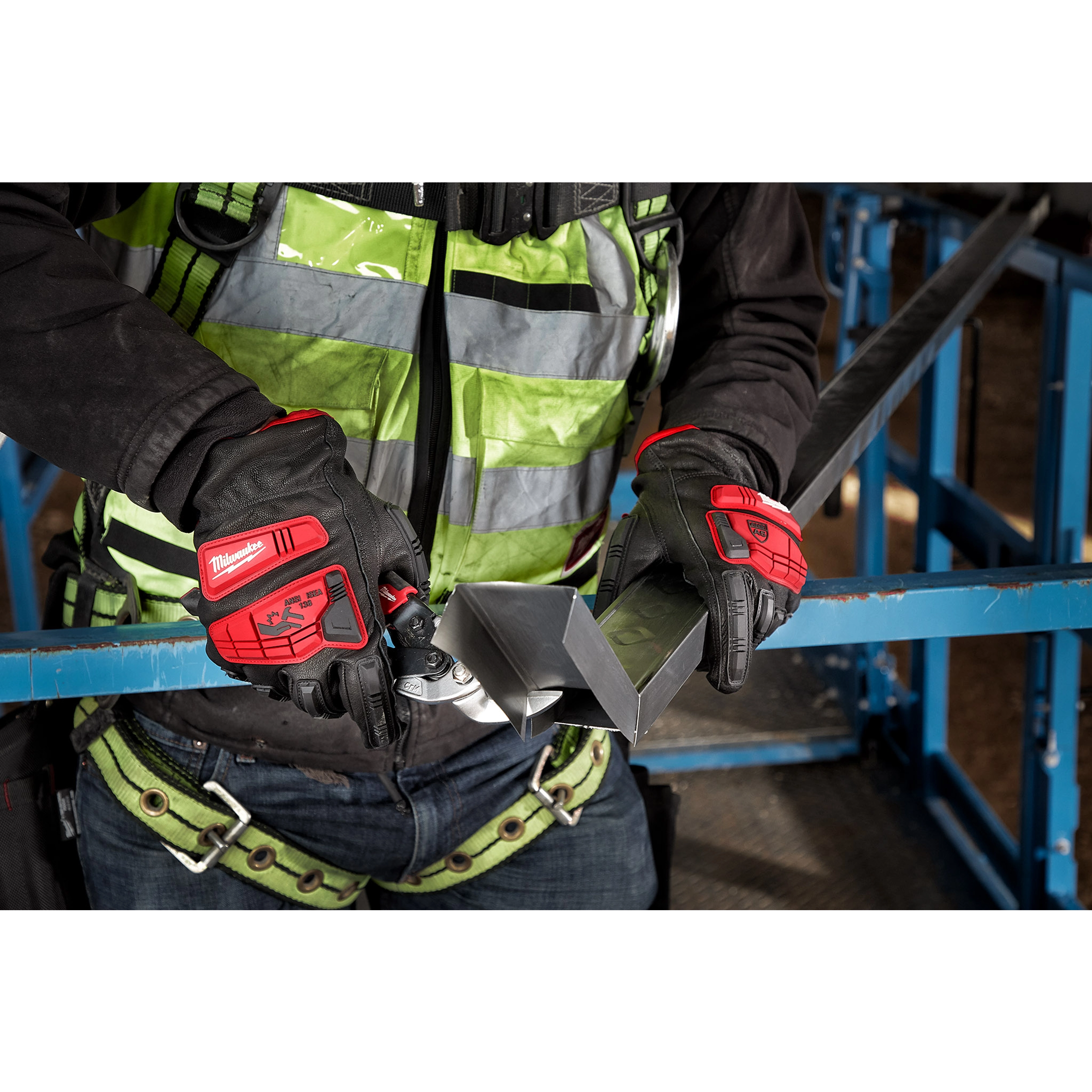 Worker wearing Impact Cut Level 5 Goatskin Leather Gloves handles a metal object while dressed in safety gear at a construction site.