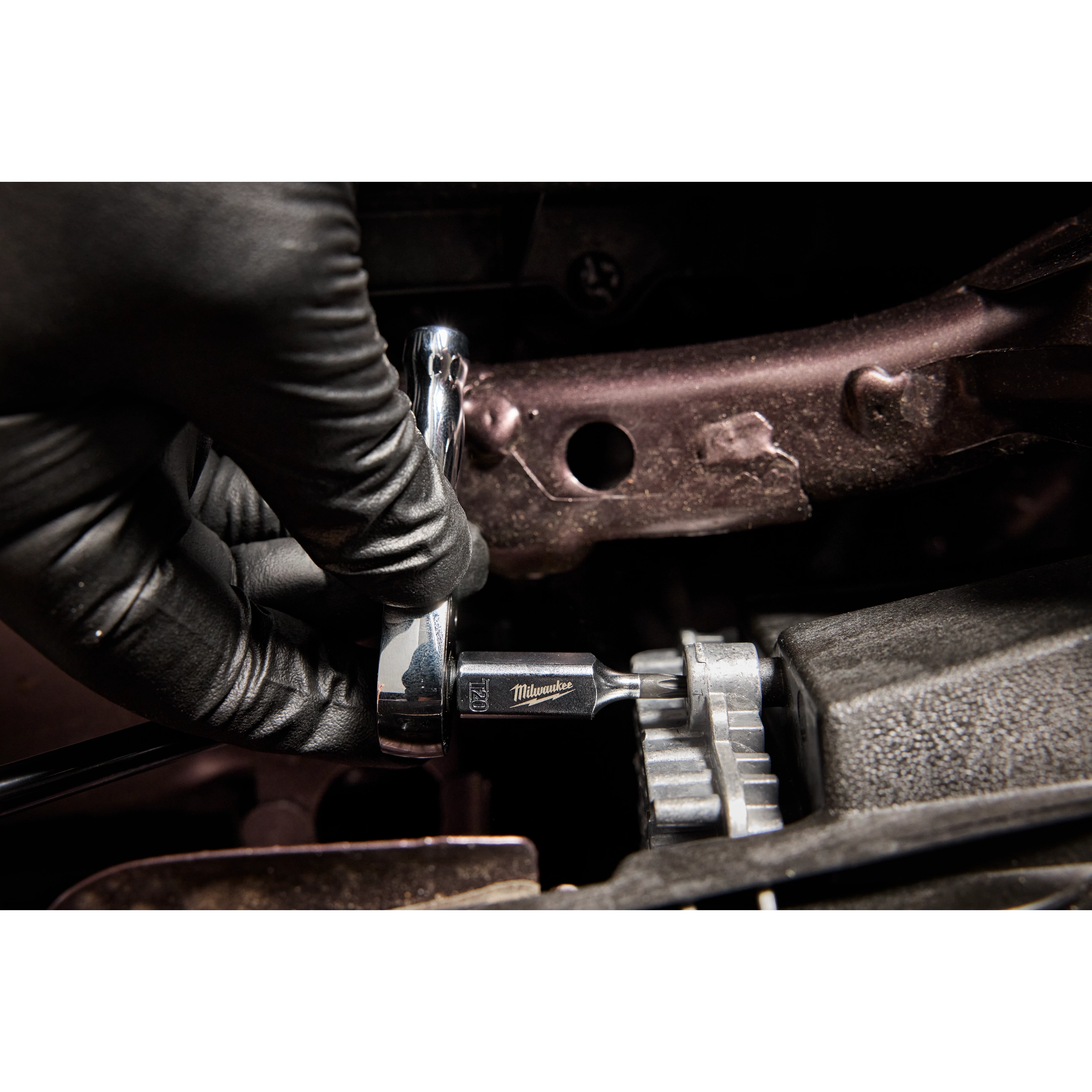 A gloved hand uses the 1/4" Drive T20 Tamper Proof TORX Bit Socket to tighten a bolt in a mechanical setting.