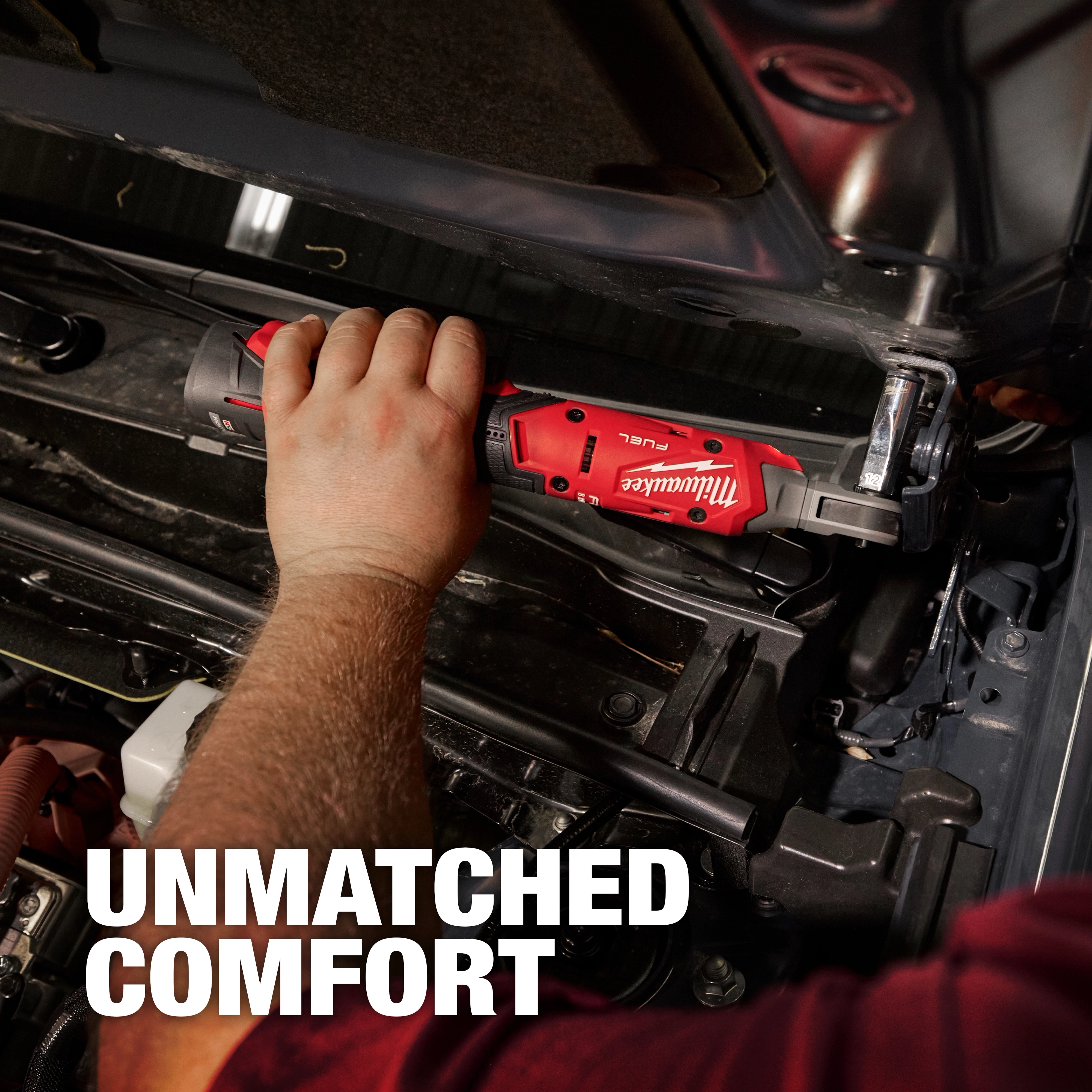A person uses an M12 FUEL™ 1/4" Ratchet on a car engine. The tool is red and black with the Milwaukee logo visible. Text reading "UNMATCHED COMFORT" appears in the bottom left corner. The image emphasizes ease of use in tight spaces.