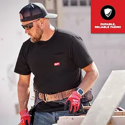 Man wearing a black GRIDIRON Pocket T-Shirt - Short Sleeve, working on a construction site, with "Durable, Reliable Fabric" text in the corner.