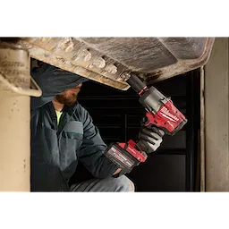Worker using M18 FUEL 3/4" High Torque Impact Wrench w/ ONE-KEY on a large metal structure.