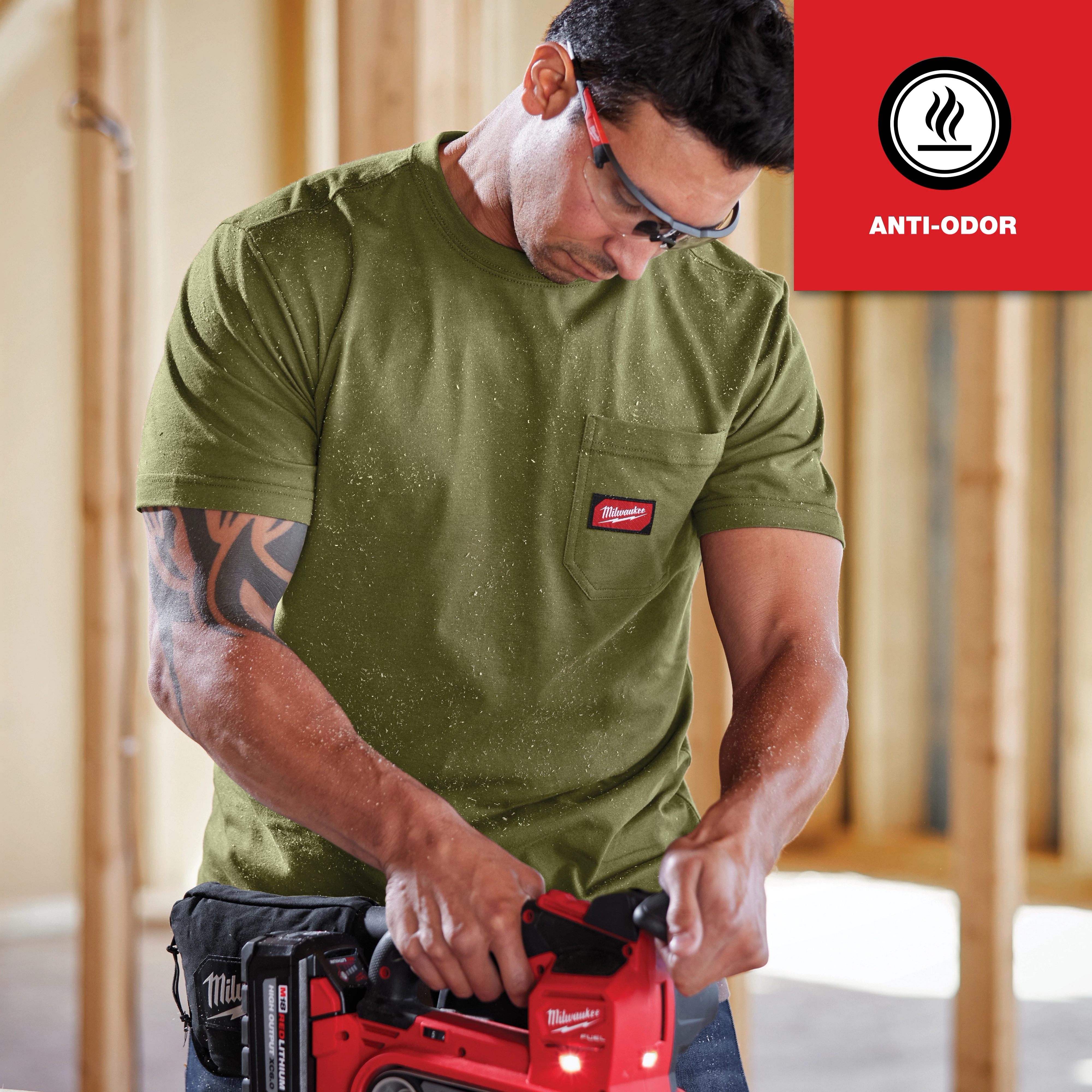 GRIDIRON Pocket T-Shirt - Short Sleeve Anti-odor in olive green, worn by a person operating a red power tool in a construction setting.