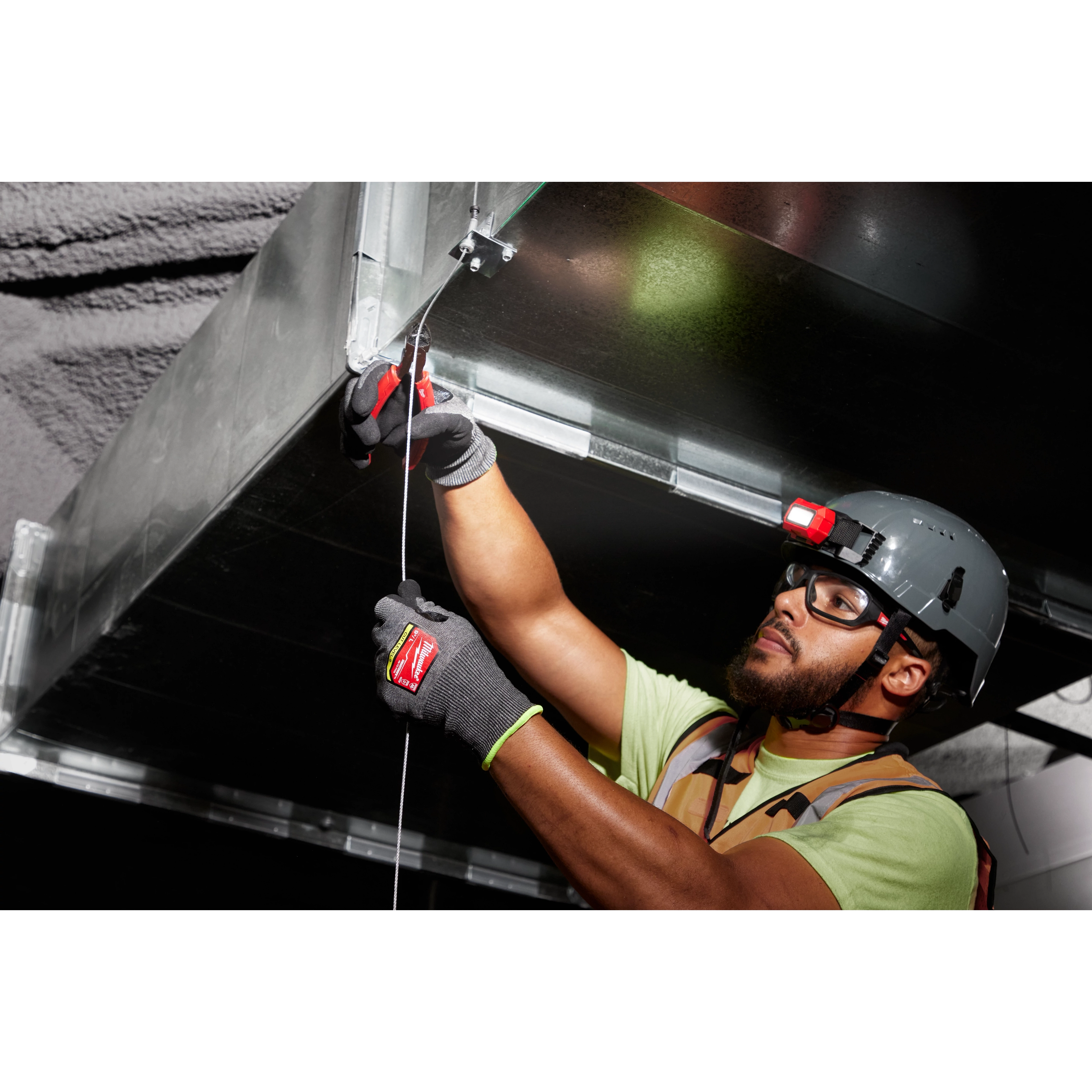 Worker wearing Cut Level 9 High-Dexterity Nitrile Dipped Gloves - L, installing a metal duct while using a headlamp.