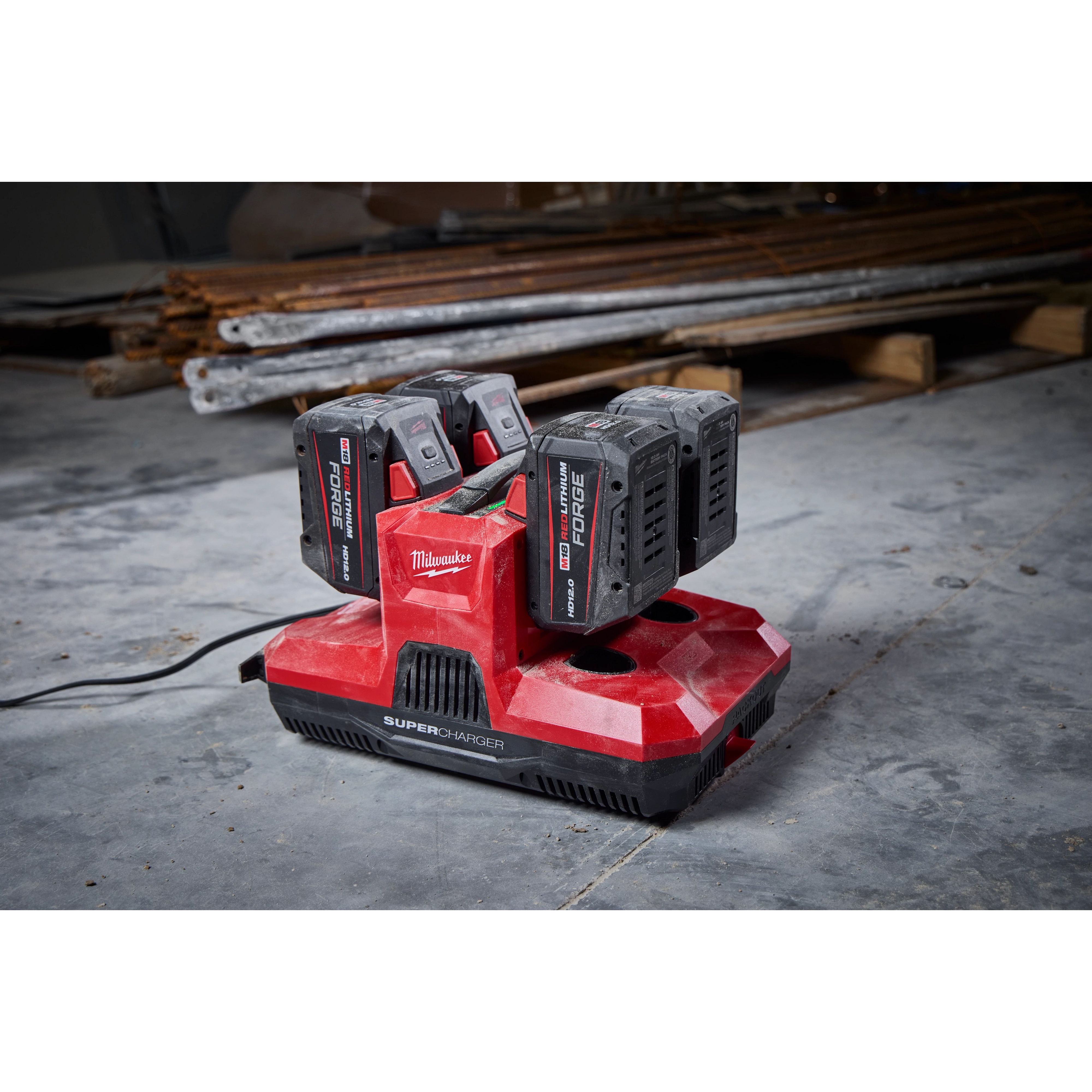 M18 & M12 Four Bay Simultaneous Super Charger with PACKOUT Compatibility; red charger with four battery slots on a workshop floor.