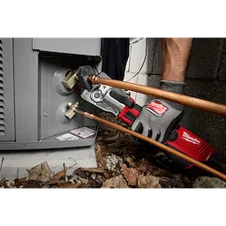 A technician uses a 3/4" ZoomLock MAX® & >B< MaxiPro® Pivoting Press Ring to connect copper pipes to an HVAC unit. The tool is connected to a red and black Milwaukee press machine.