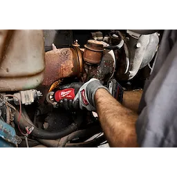 Gloved hands use an M12 FUEL 1/4" Straight Die Grinder on a rusted engine component.