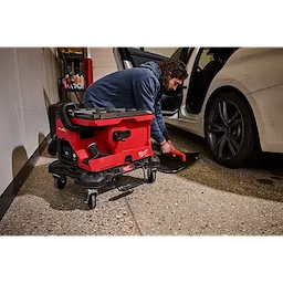 Person using an M18 FUEL 4 Gallon Wet/Dry Vacuum w/ PACKOUT Compatibility & VACLINK beside a car interior.