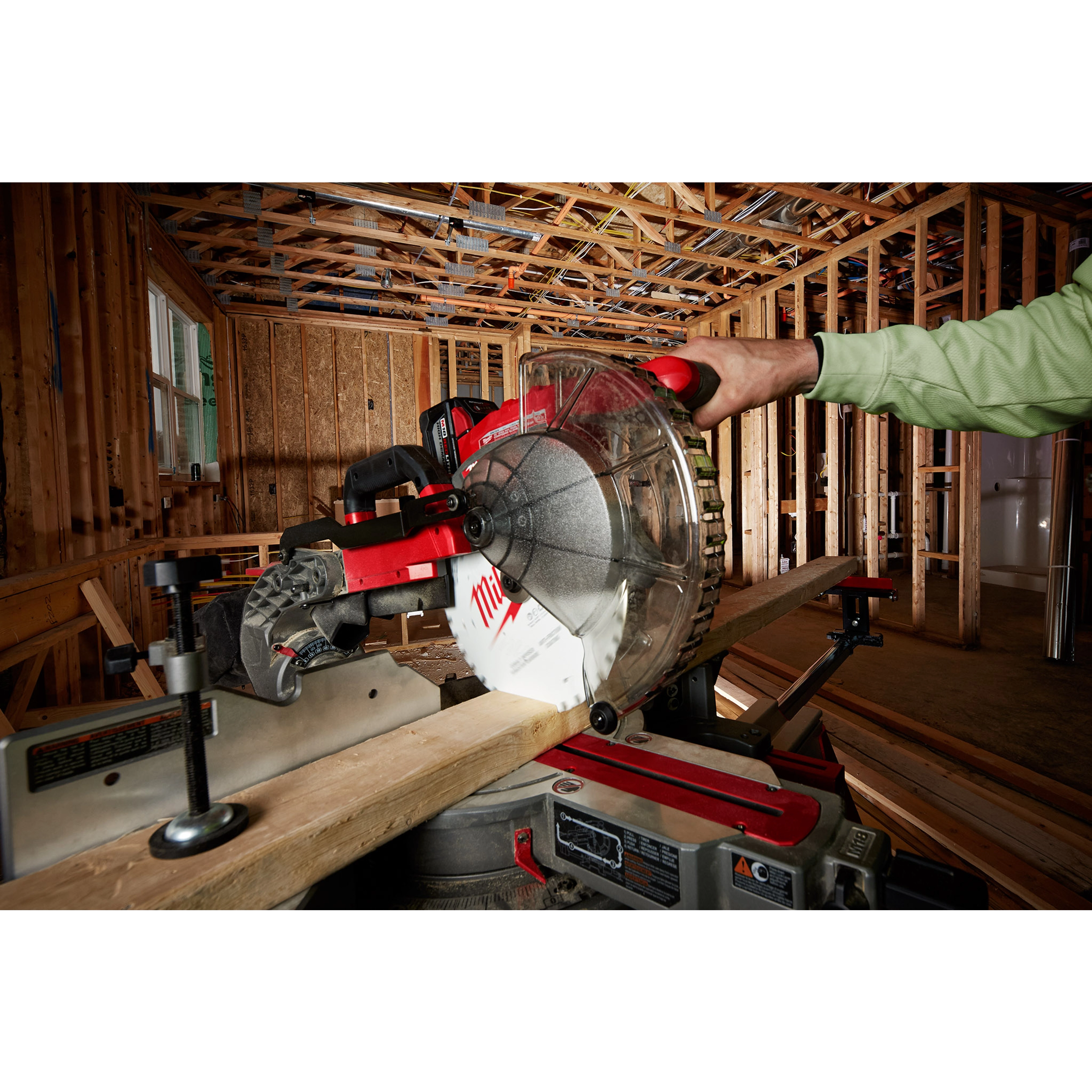 Person using the 10" 24T Ripping Circular Saw Blade on a miter saw to cut a wooden plank in a construction setting.