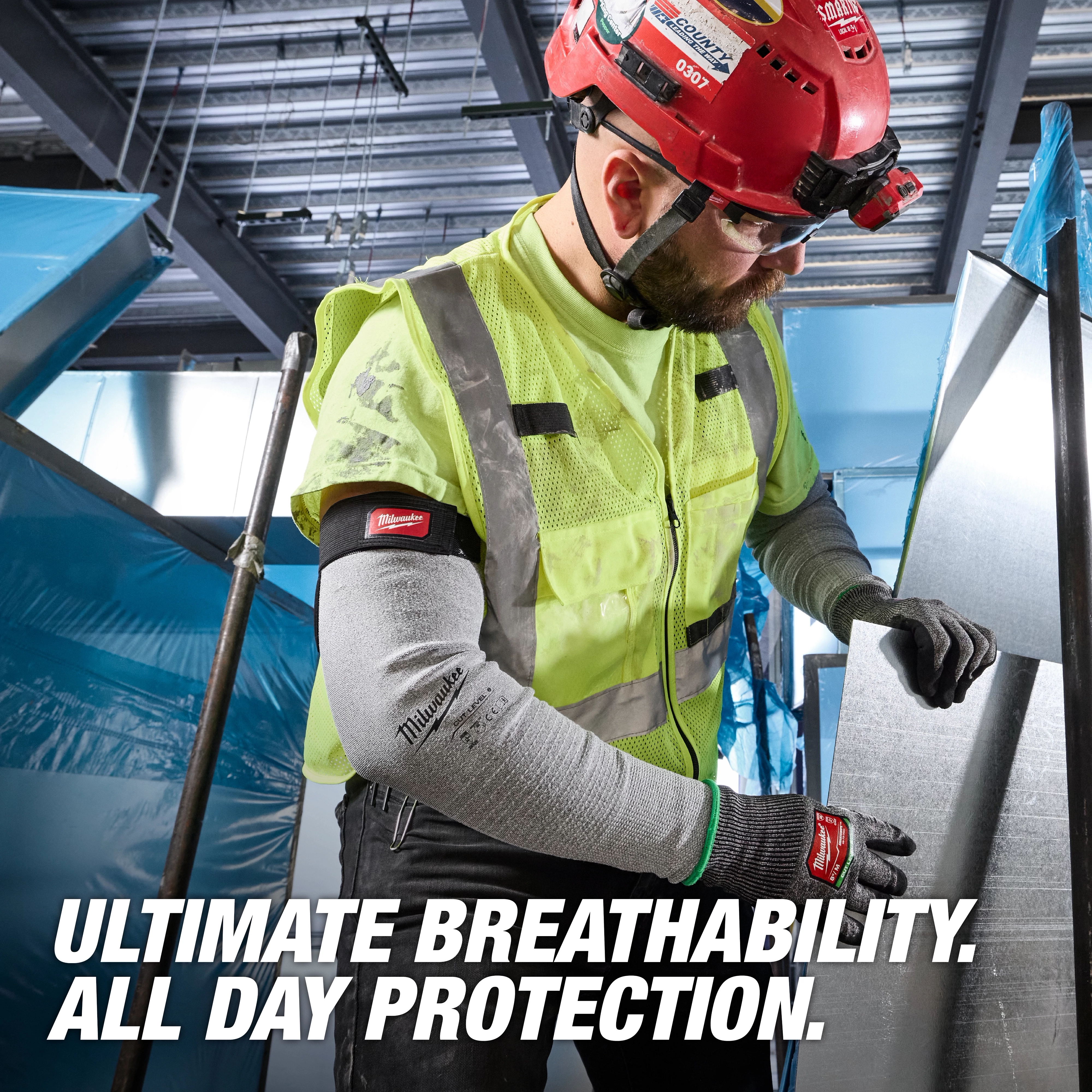 Worker wearing Cut Level 6 Protective Sleeves - 16" while handling a large metal sheet in an industrial setting.