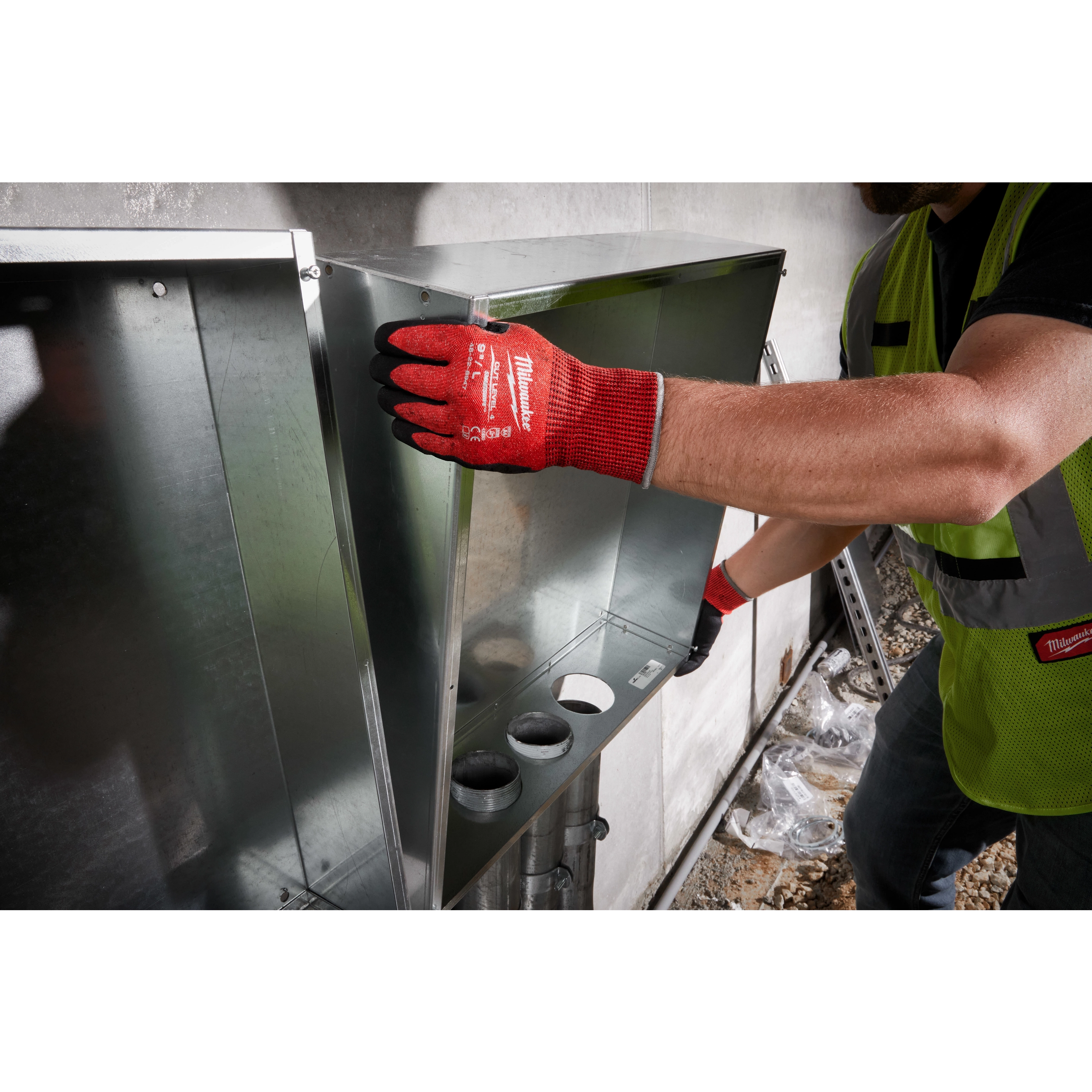 A worker wearing a Cut Level 4 Nitrile Dipped Glove - L in red is handling a metal duct in an industrial environment.