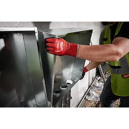 A worker wearing a Cut Level 4 Nitrile Dipped Glove - L in red is handling a metal duct in an industrial environment.