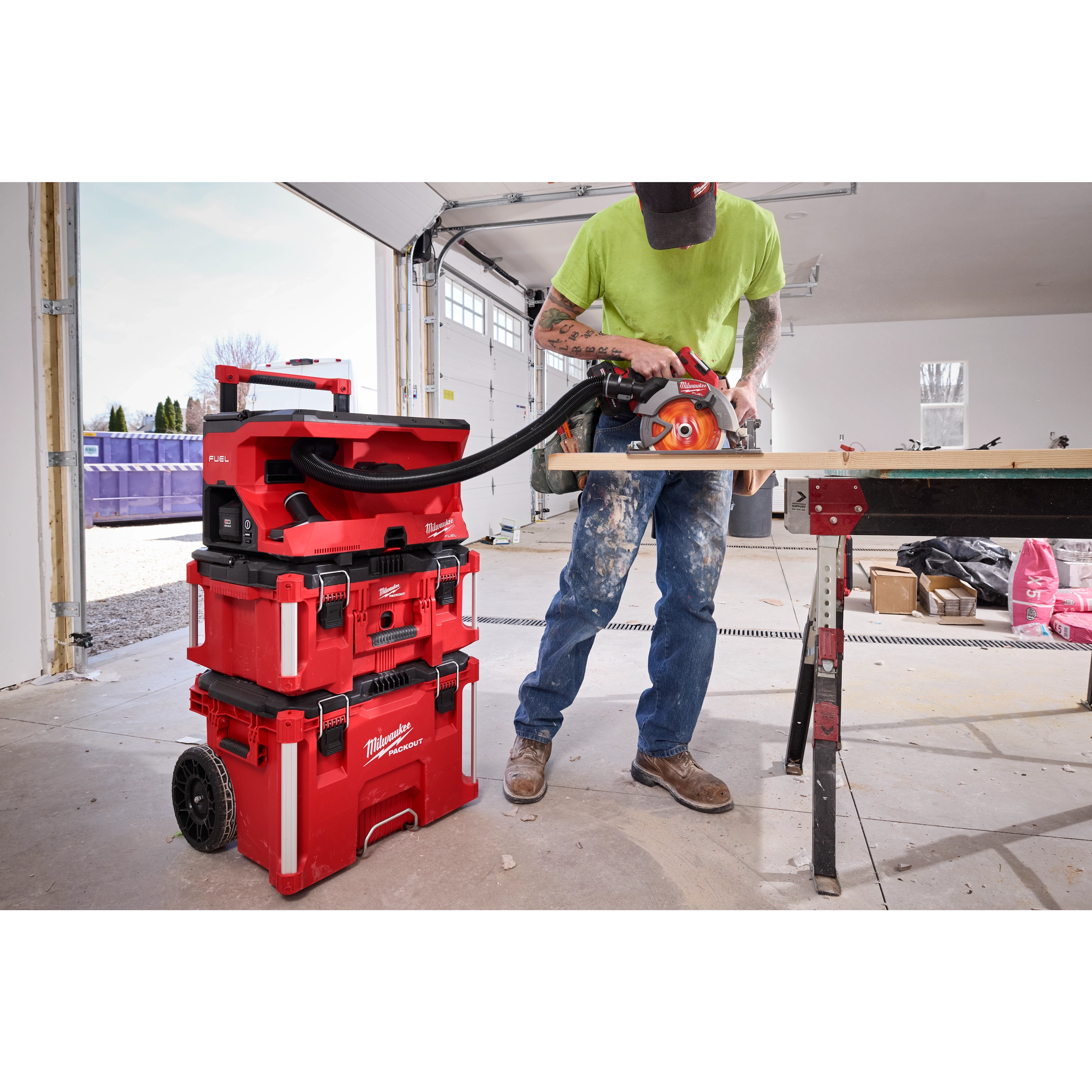 Worker cutting wood with saw connected to M18 FUEL 4 Gallon Wet/Dry Vacuum w/ PACKOUT Compatibility & VACLINK..