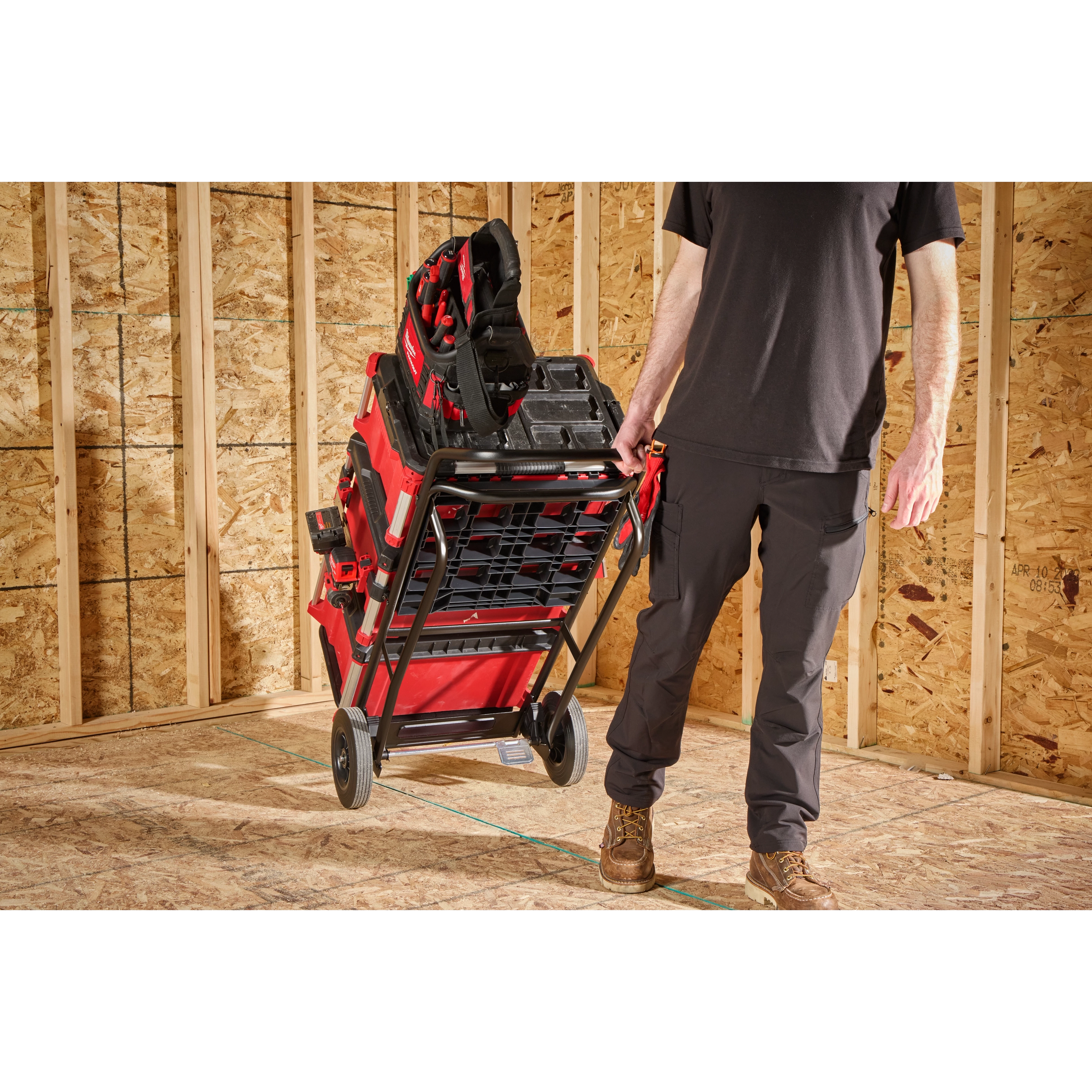 Person pulling a loaded PACKOUT Hand Truck across a plywood floor in a framed room.