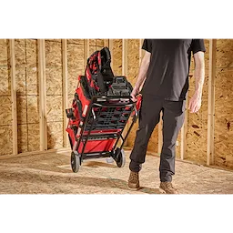 Person pulling a loaded PACKOUT Hand Truck across a plywood floor in a framed room.