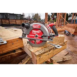 The M18 FUEL 10-1/4" Rear Handle Circular Saw is placed on a construction site workbench, surrounded by timber and tools.