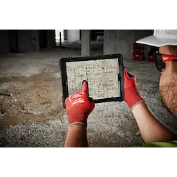 A person wearing Cut Level 4 Nitrile Dipped Glove - L uses a tablet to view construction blueprints at a worksite.