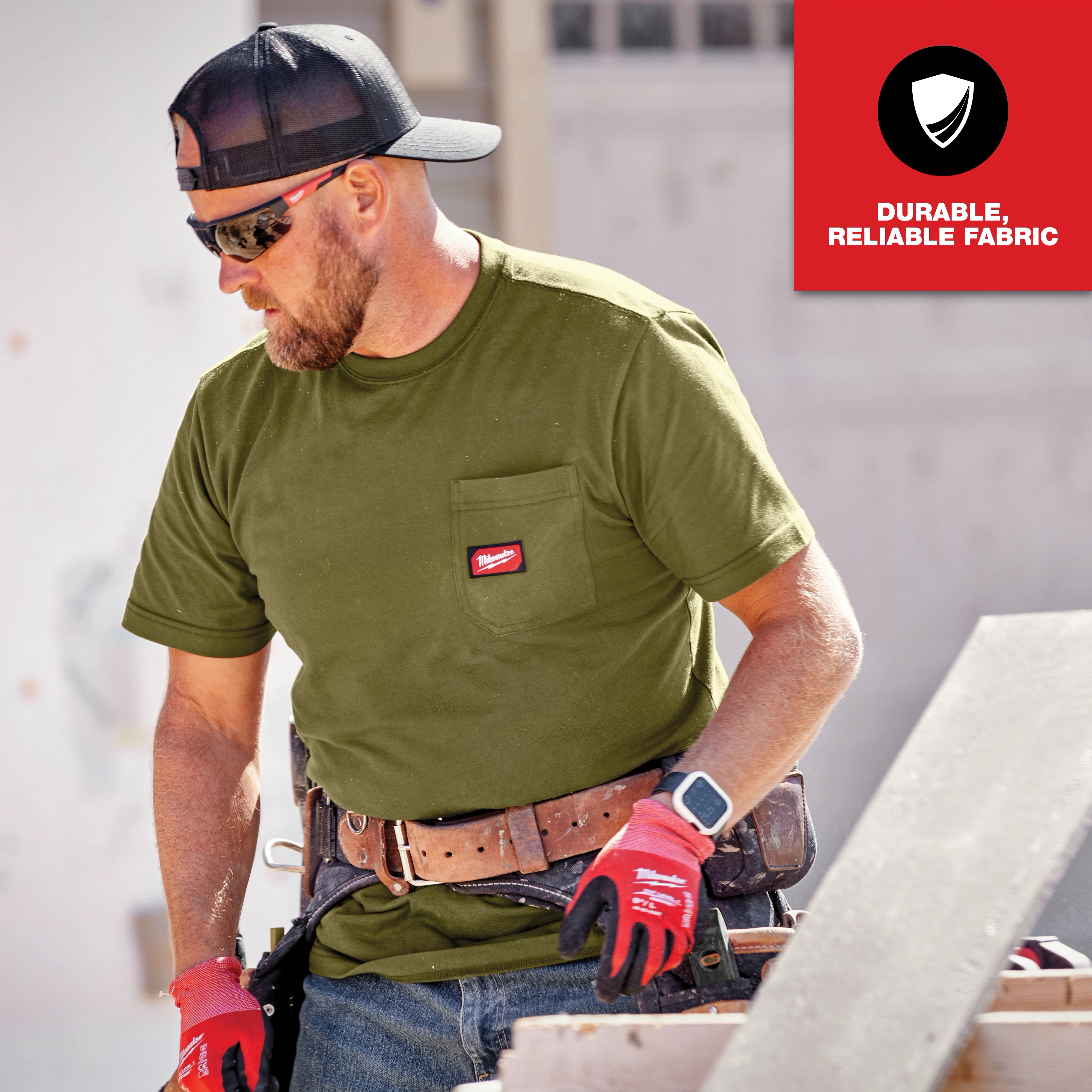 The GRIDIRON Pocket T-Shirt - Short Sleeve is shown in olive green, worn by a worker with a tool belt, highlighting its durability and reliable fabric.