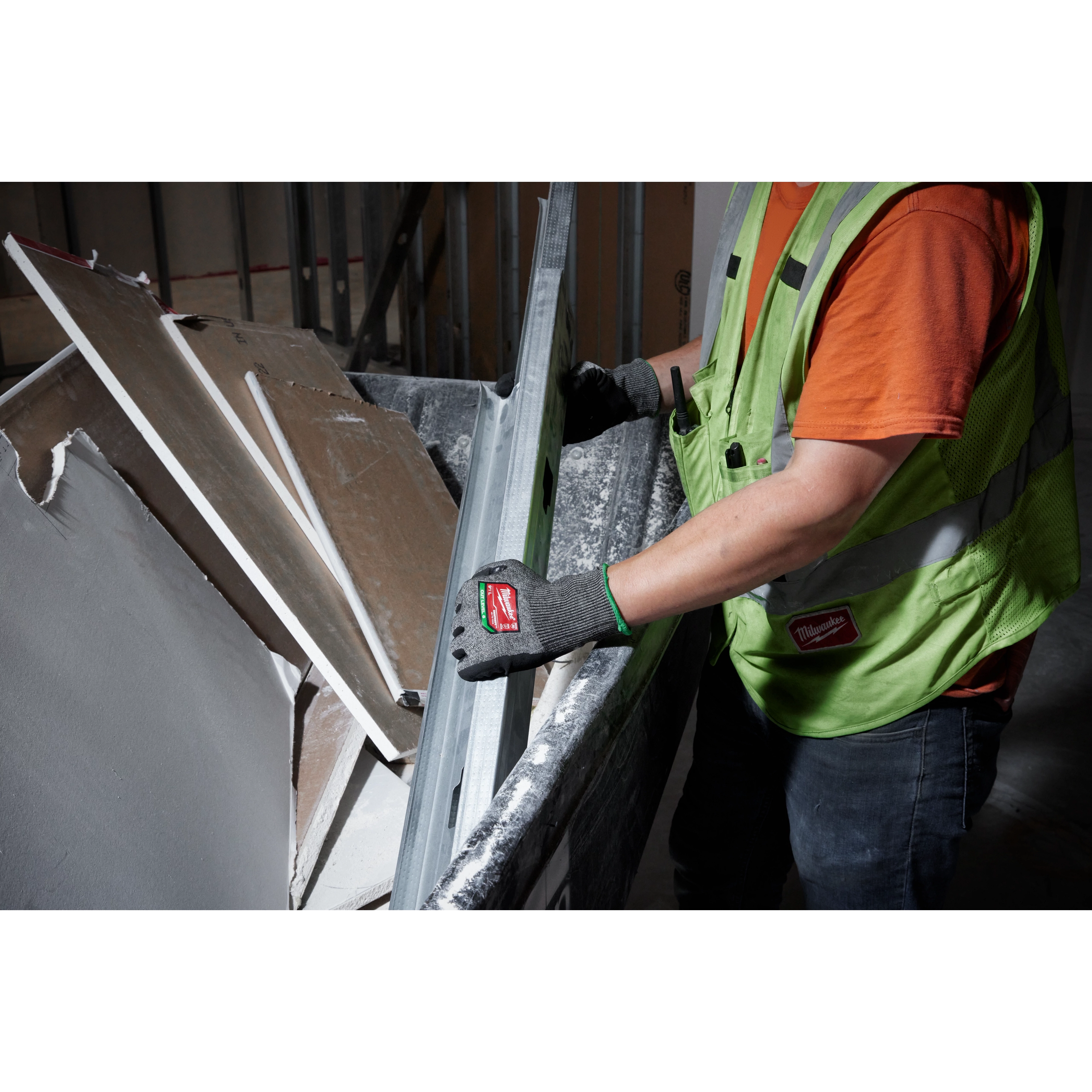 A worker wearing a high-visibility vest uses Cut Level 6 High-Dexterity Nitrile Dipped Gloves - L to handle metal and drywall debris. The gloves provide protection and grip for handling sharp or rough materials.