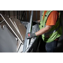 A worker wearing a high-visibility vest uses Cut Level 6 High-Dexterity Nitrile Dipped Gloves - L to handle metal and drywall debris. The gloves provide protection and grip for handling sharp or rough materials.