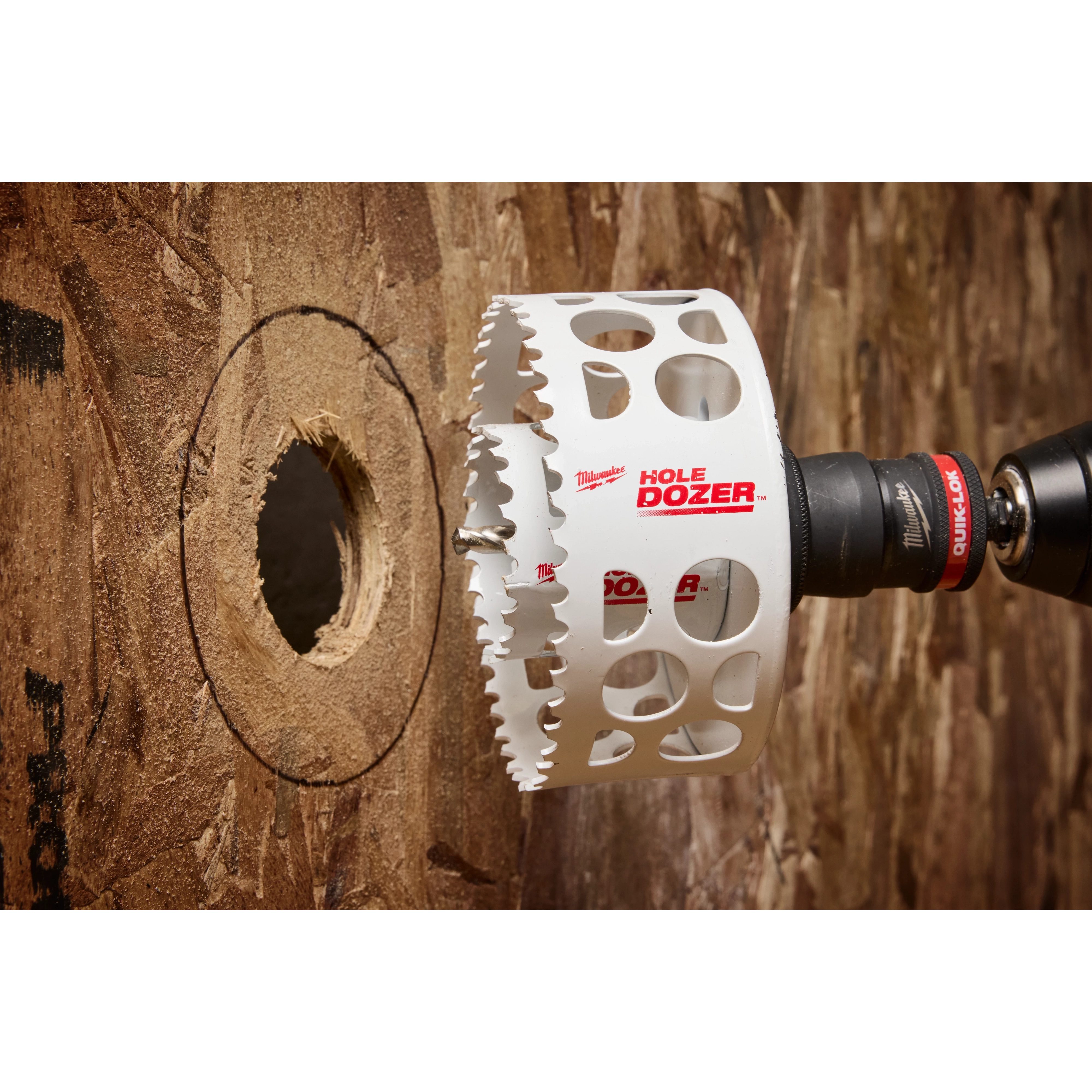 The image shows a Hole Enlargement Adapter for QUIK-LOK™ Arbor attached to a drill, cutting a larger hole in a wooden surface. The adapter, labeled "HOLE DOZER," is designed to increase the diameter of existing holes.