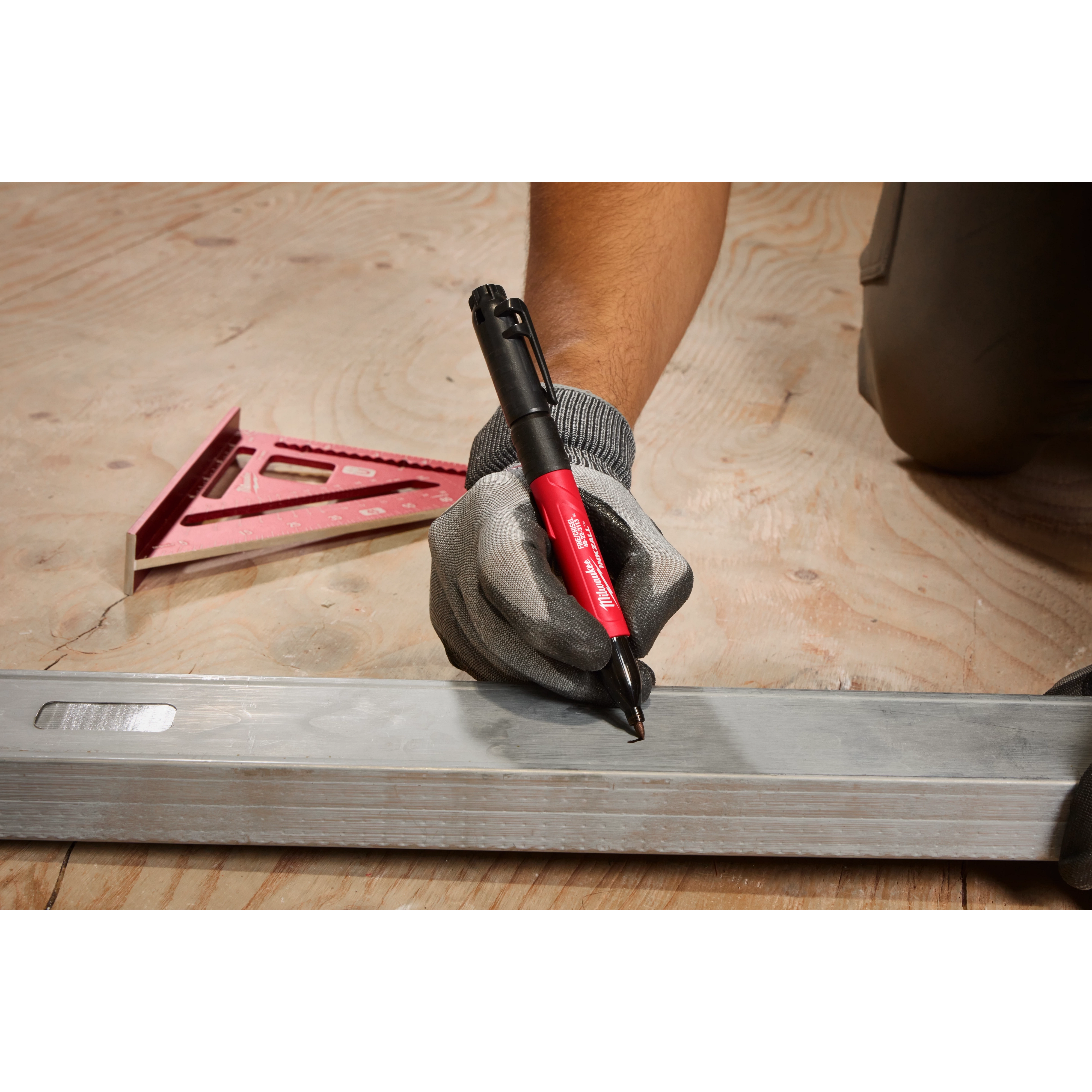 A gloved hand uses an INKZALL Double-Sided Black jobsite marker. Its fine point and chisel tip mark a metal surface. The marker's body is red, and white text specifies its brand and type.