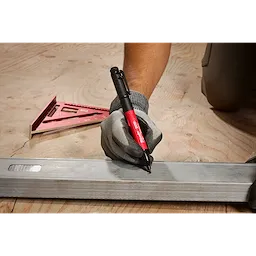 A gloved hand uses an INKZALL Double-Sided Black jobsite marker. Its fine point and chisel tip mark a metal surface. The marker's body is red, and white text specifies its brand and type.