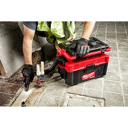 A worker cleans a floor using the M18 FUEL PACKOUT 2.5 Gallon Wet/Dry Vacuum, emphasizing its portability and efficiency on job sites.