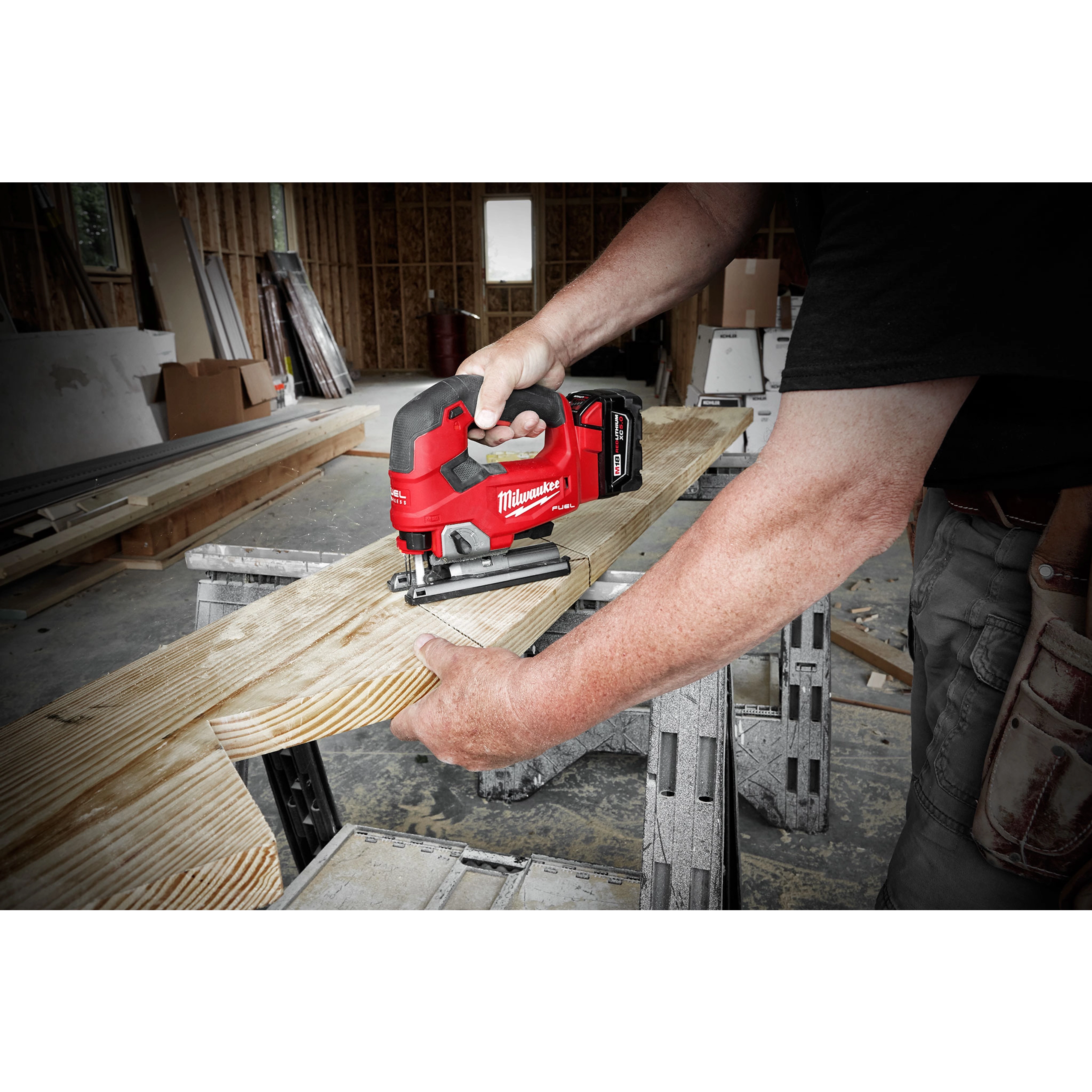 A person using the M18 FUEL Jigsaw, D-Handle to cut a piece of wood in a workshop environment.