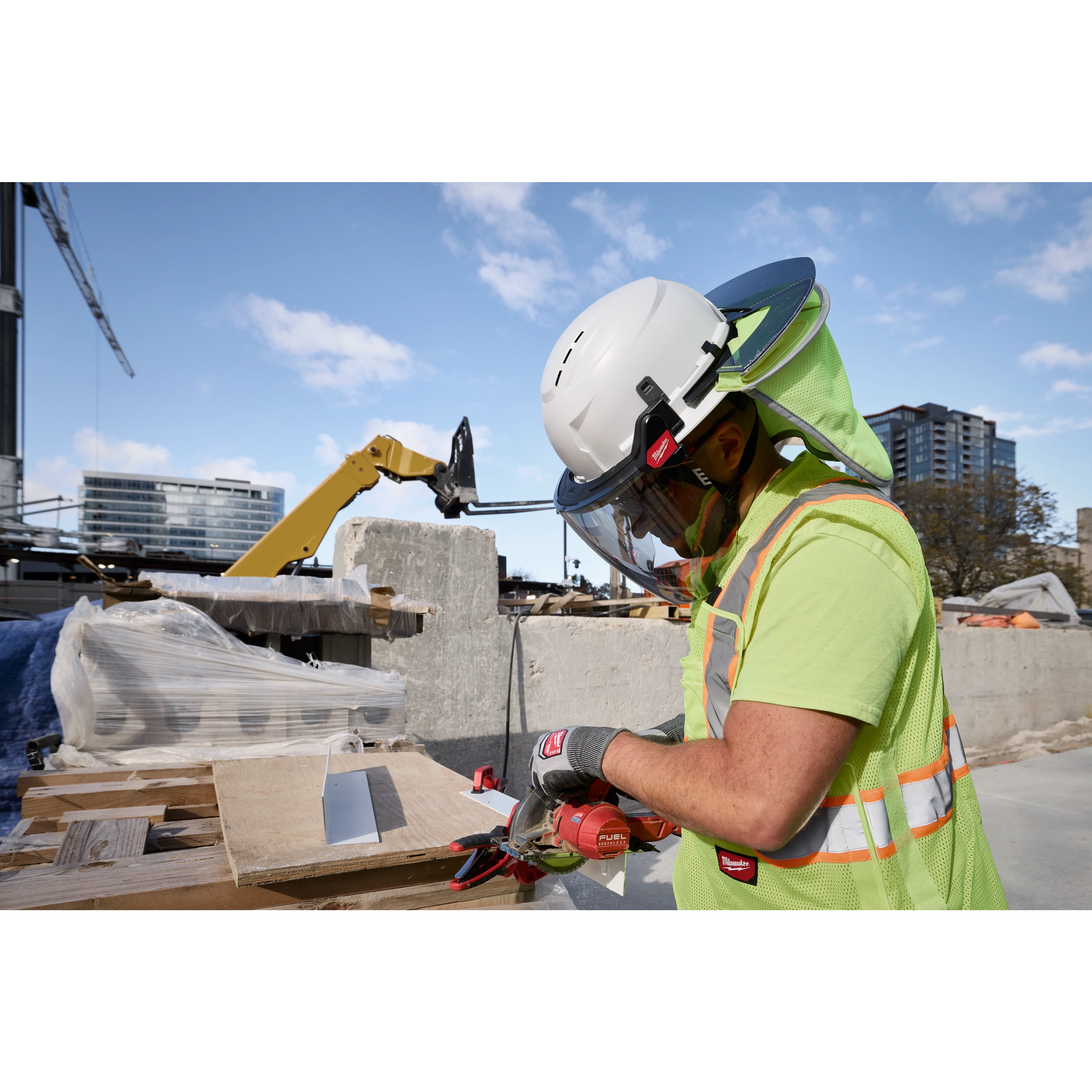 A construction worker wearing a BOLT 4PT White Full Brim Vented Safety Helmet - Type 2, Class C, operating a tool at a construction site.