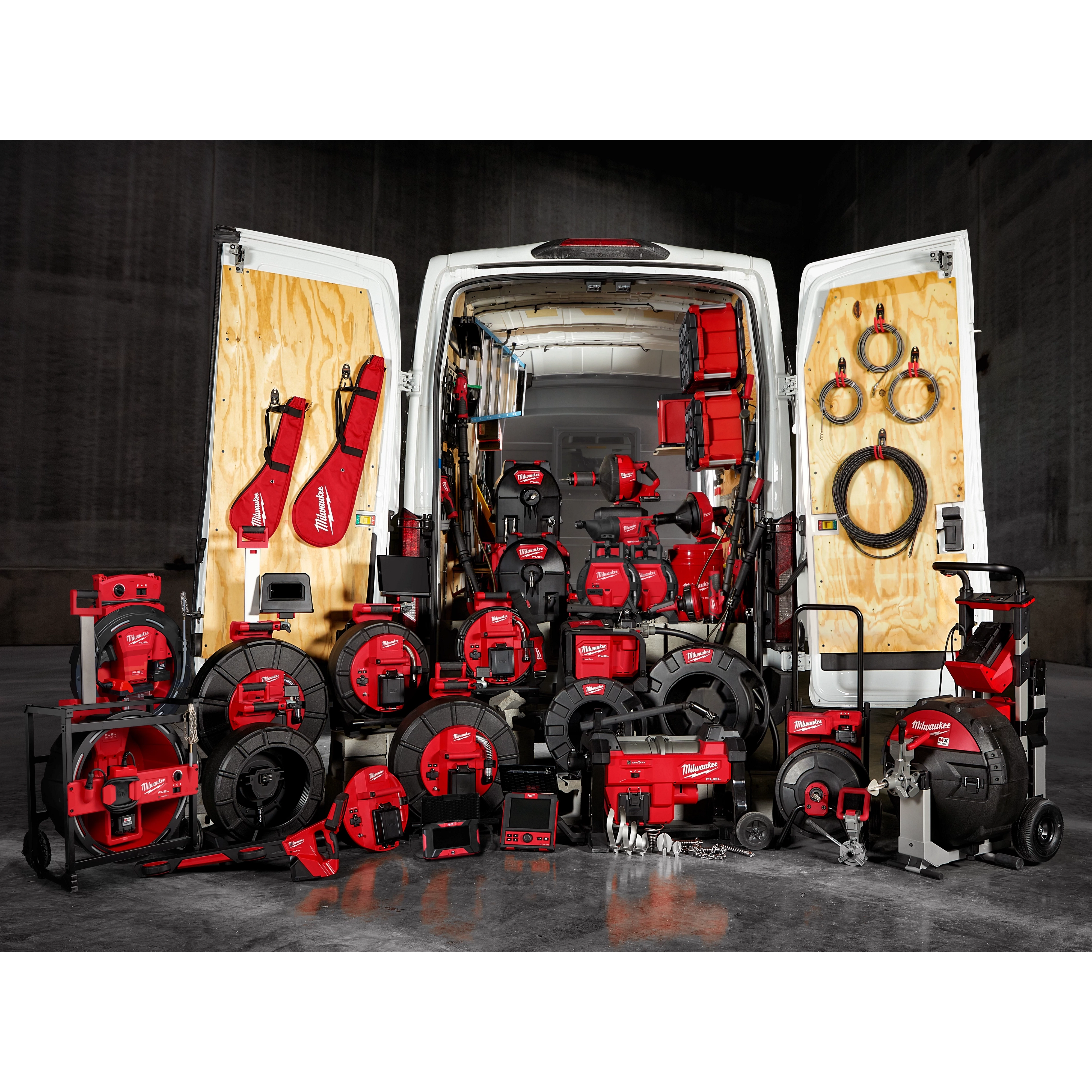 The image shows a van with its rear doors open, revealing a wide array of red and black sewer and drain cleaning equipment arranged both inside and in front of the van. The tools are part of the January 2025 Sewer & Drain Cleaning Family collection.