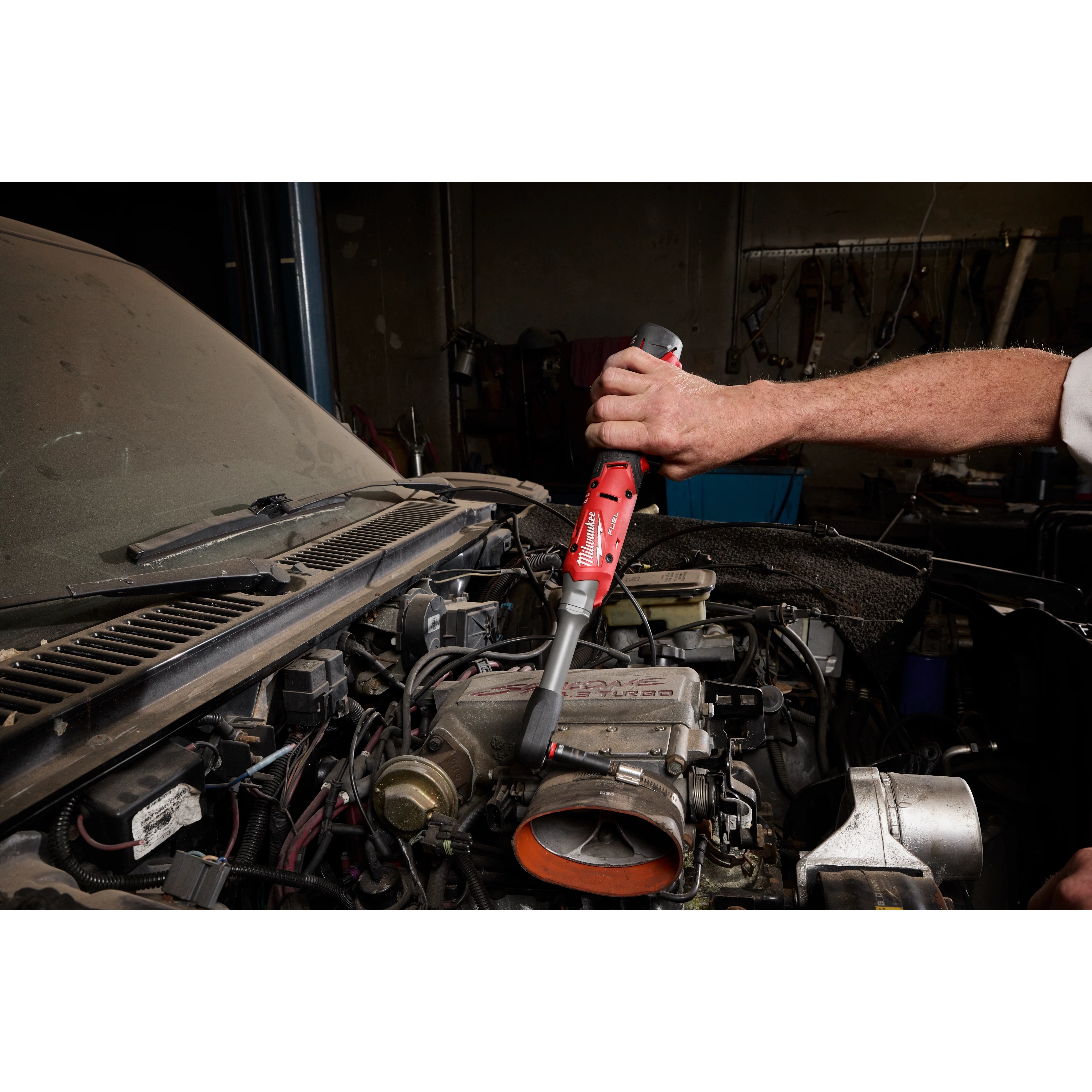 M12 FUEL 1/2" Extended Reach Ratchet being used to work on a car engine in a garage.